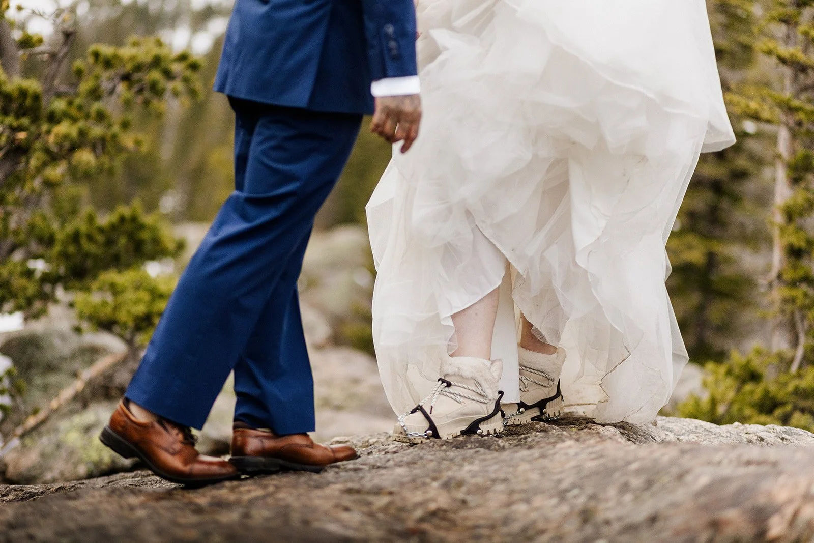 Close up of his dress shoes and her hiking boots on the rock