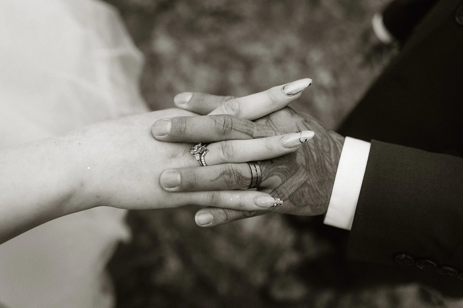 Black and white close up of their hands together showing both wedding rings