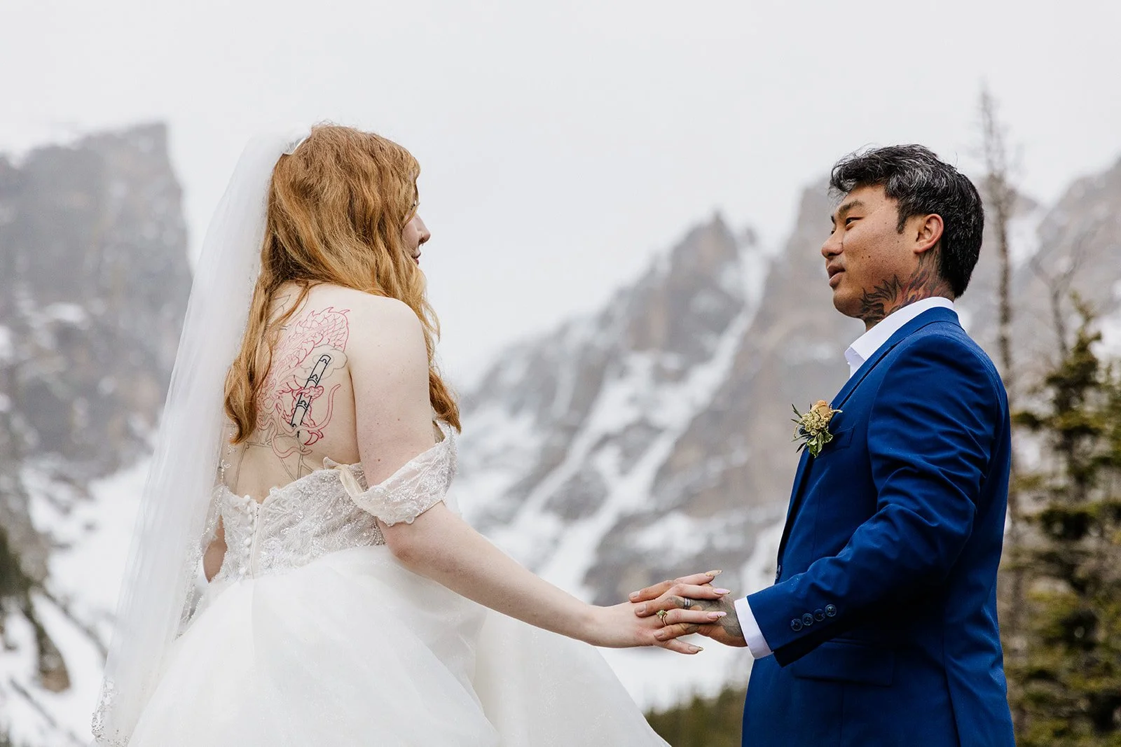 Couple holding hands at Dream Lake, her back tattoo showing above her dress