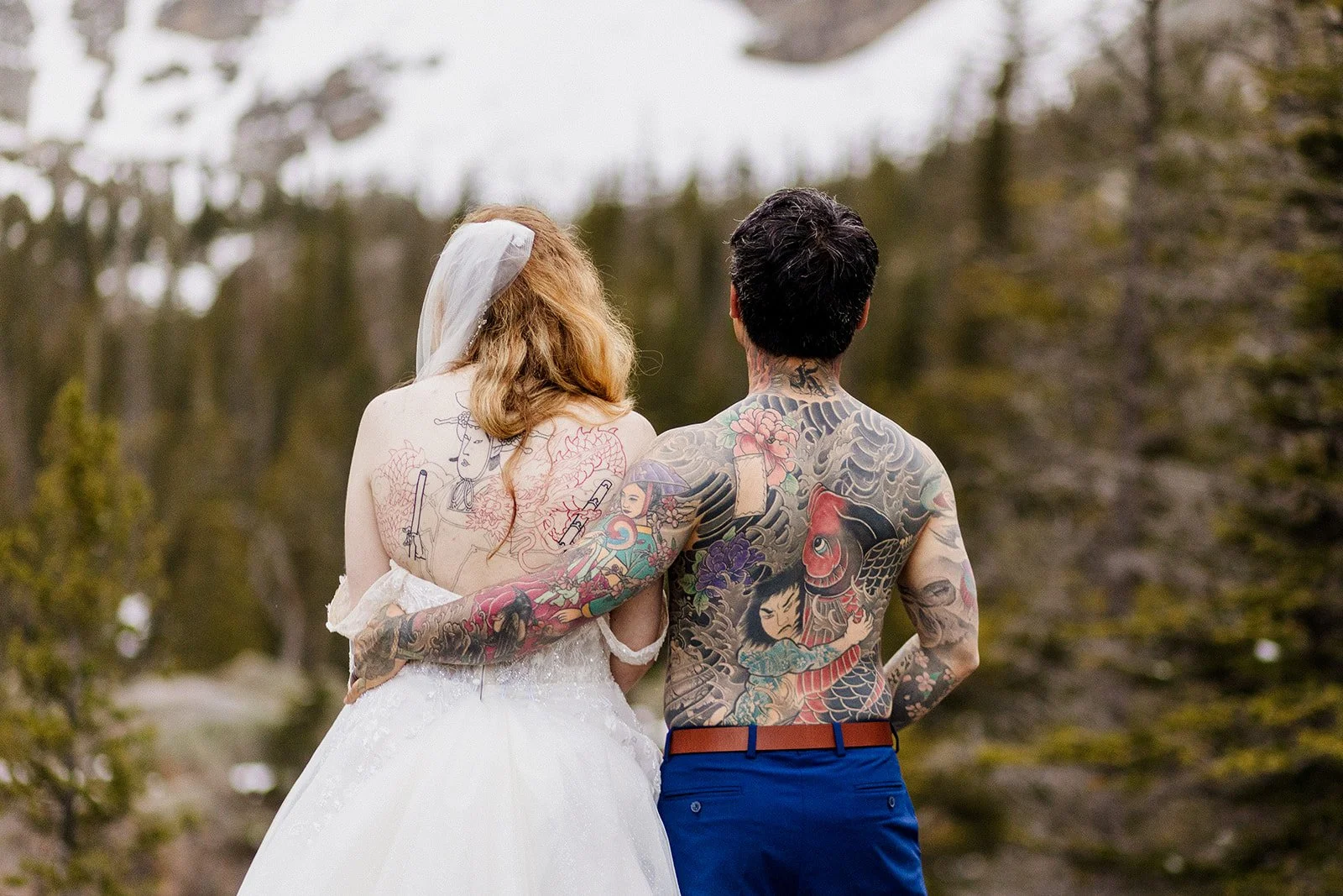 Couple from behind with their arms around each other, showing both of their back tattoos