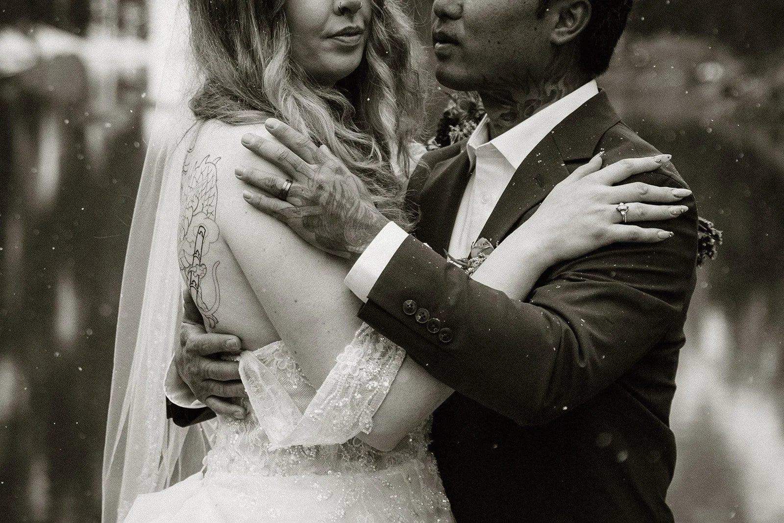 Black and white close up of the couple holding each other as snow falls