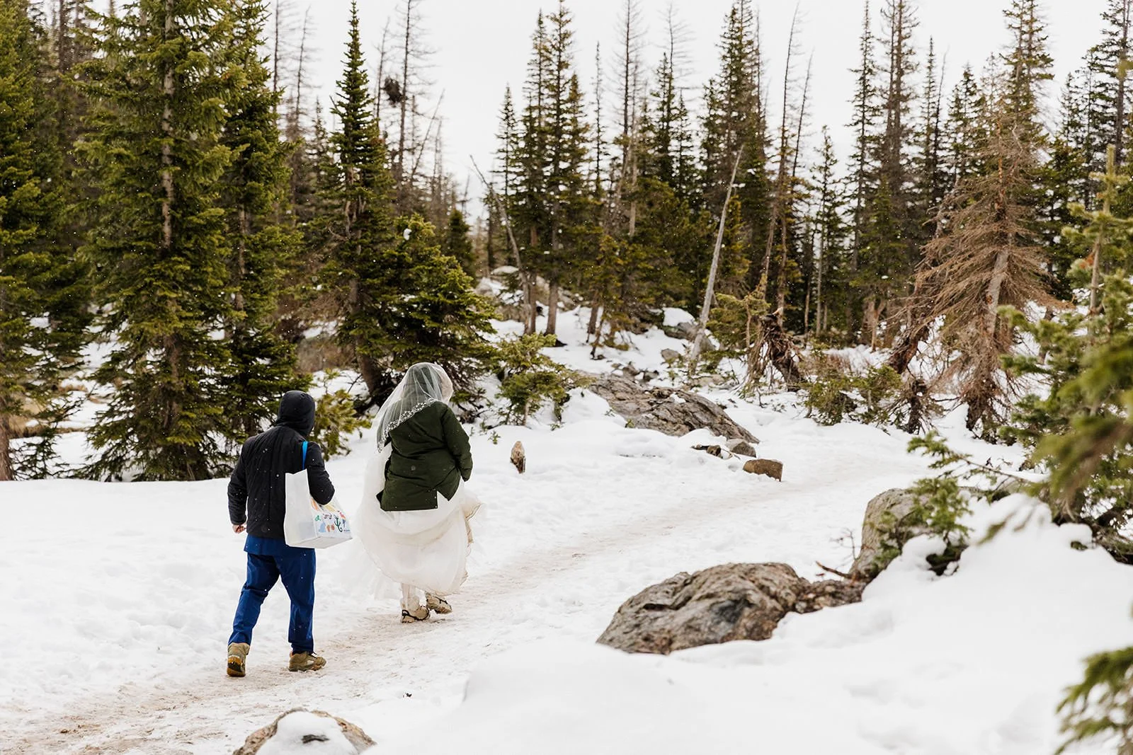 Couple hiking back down the snowy trail in their coats