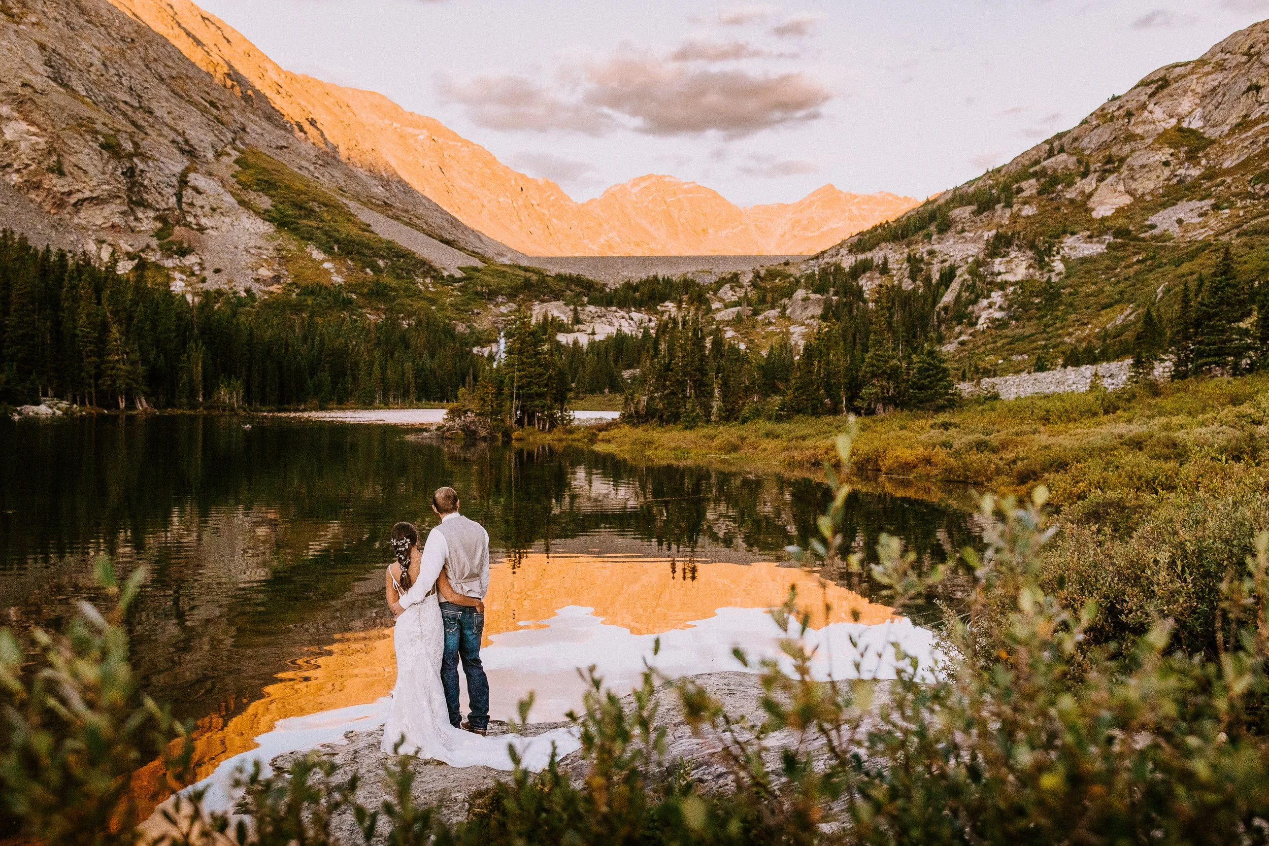 Couple at a Breckenridge elopement spot on the edge of an alpine lake, with sunset light on the peaks