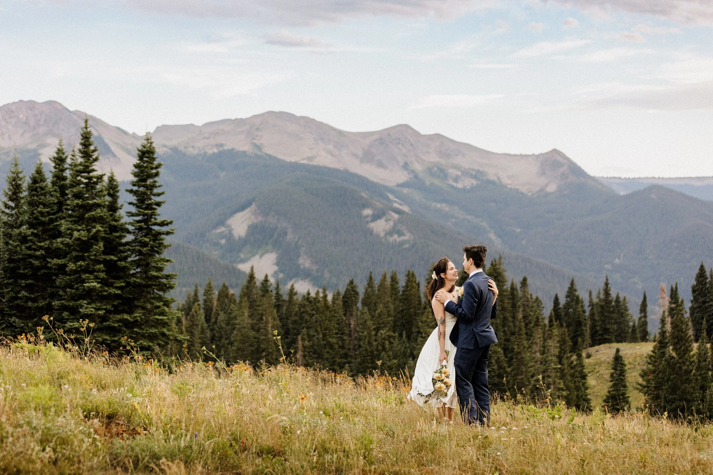 A couple in wedding attire elopes on a hillside at Lake Irwin in Crested Butte