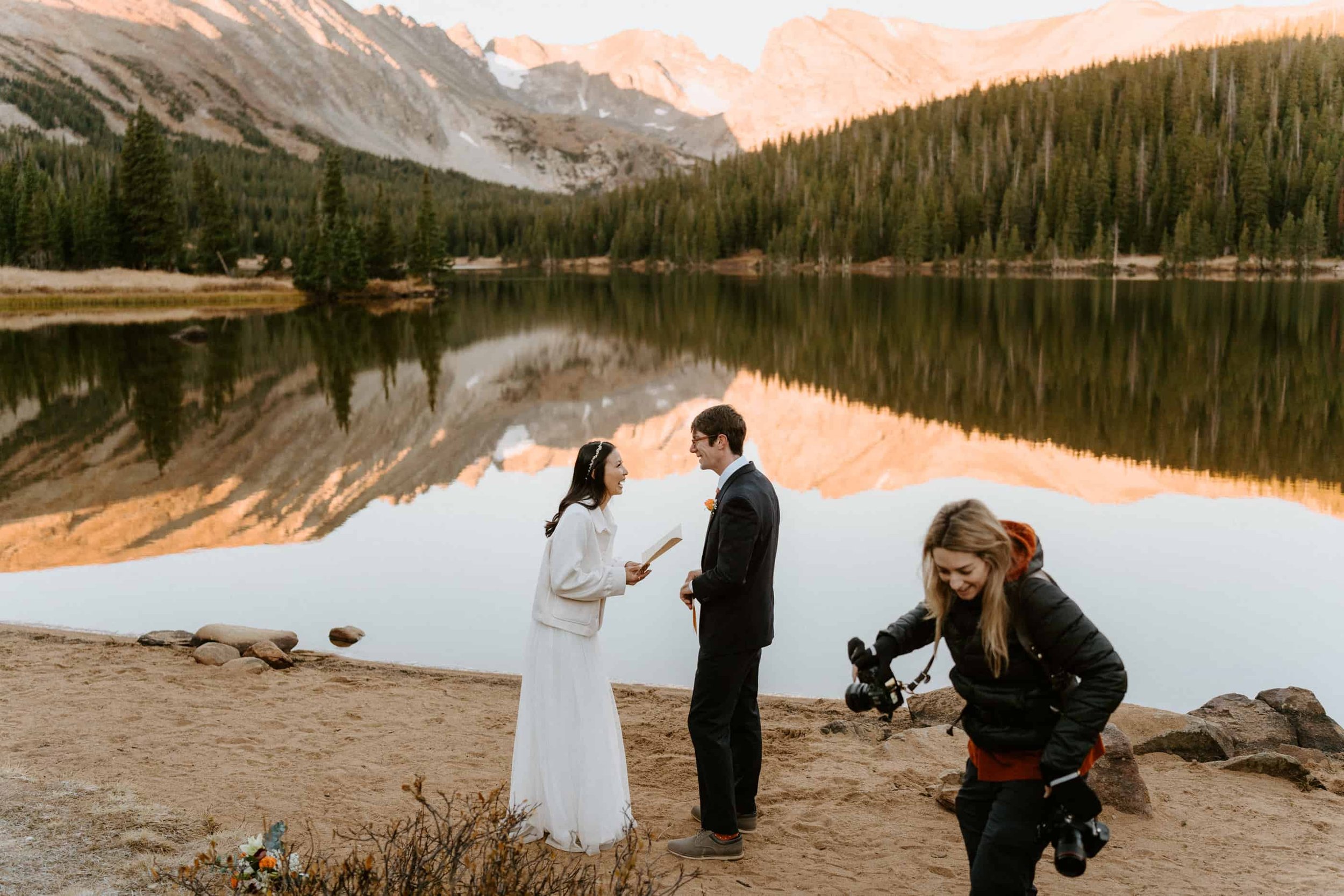 Outdoor wedding ceremony beside a Colorado alpine lake with mountains behind