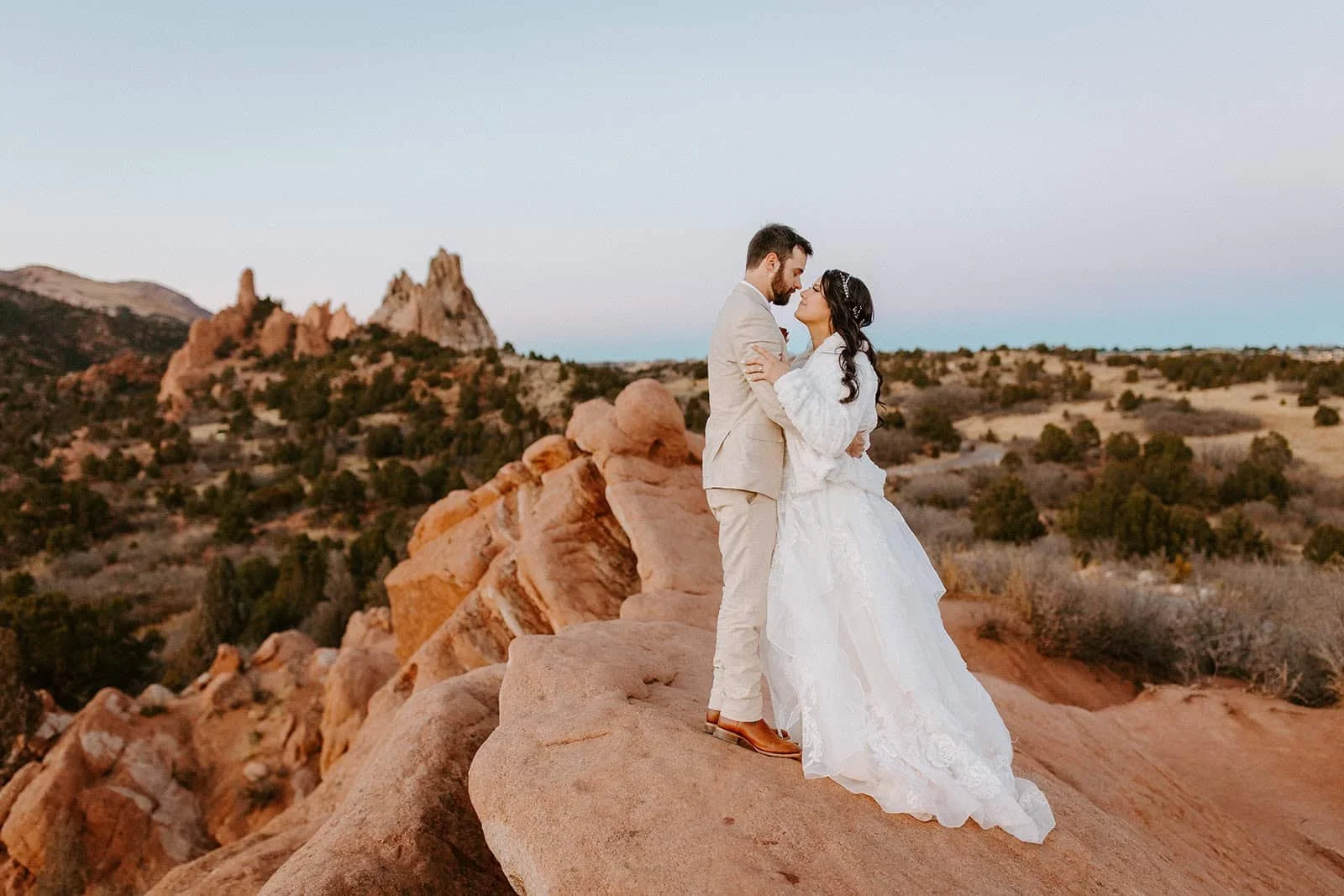 A couple in wedding clothes kisses on the red rocks at Garden of the Gods in Colorado Springs