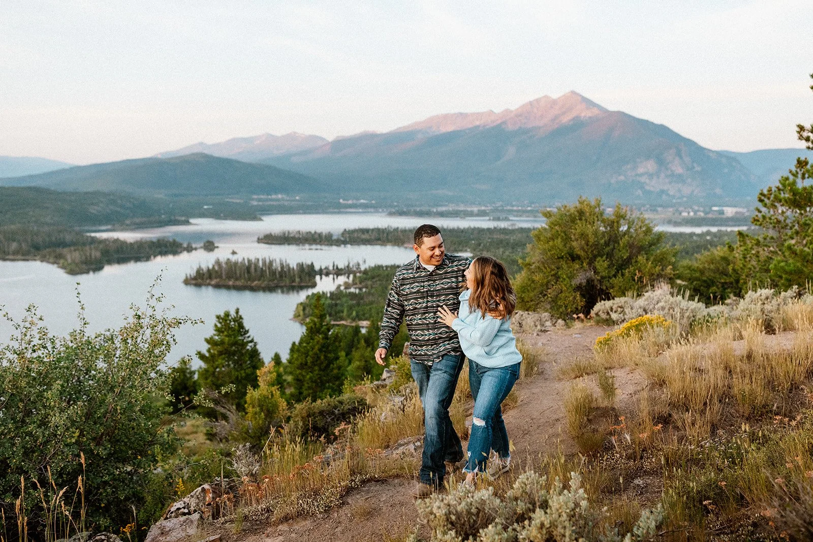 A laughing couple on the trail above Lake Dillon with the mountains glowing at sunset