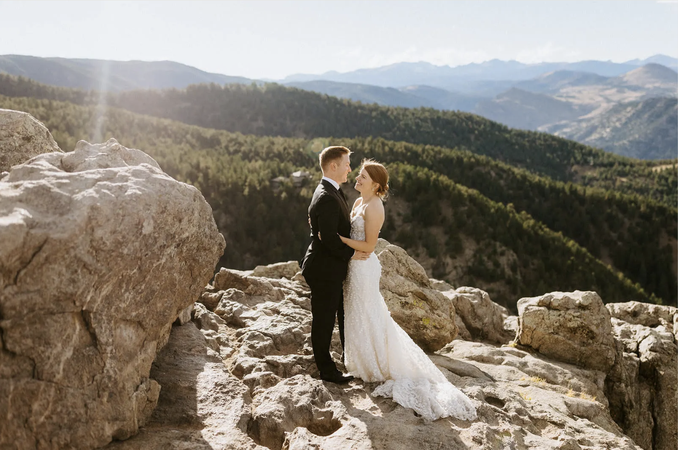 Bride and groom holding hands on a rocky mountain overlook in Boulder, Colorado at sunset