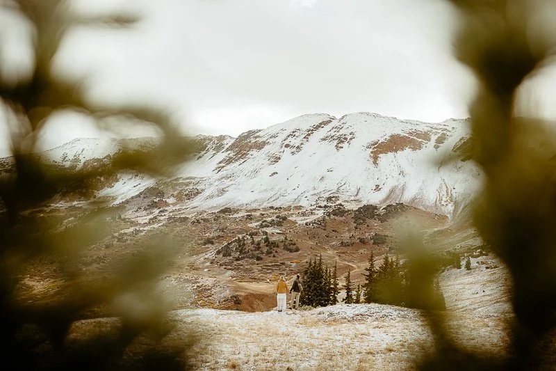 A couple stands on a snowy mountain top in Crested Butte