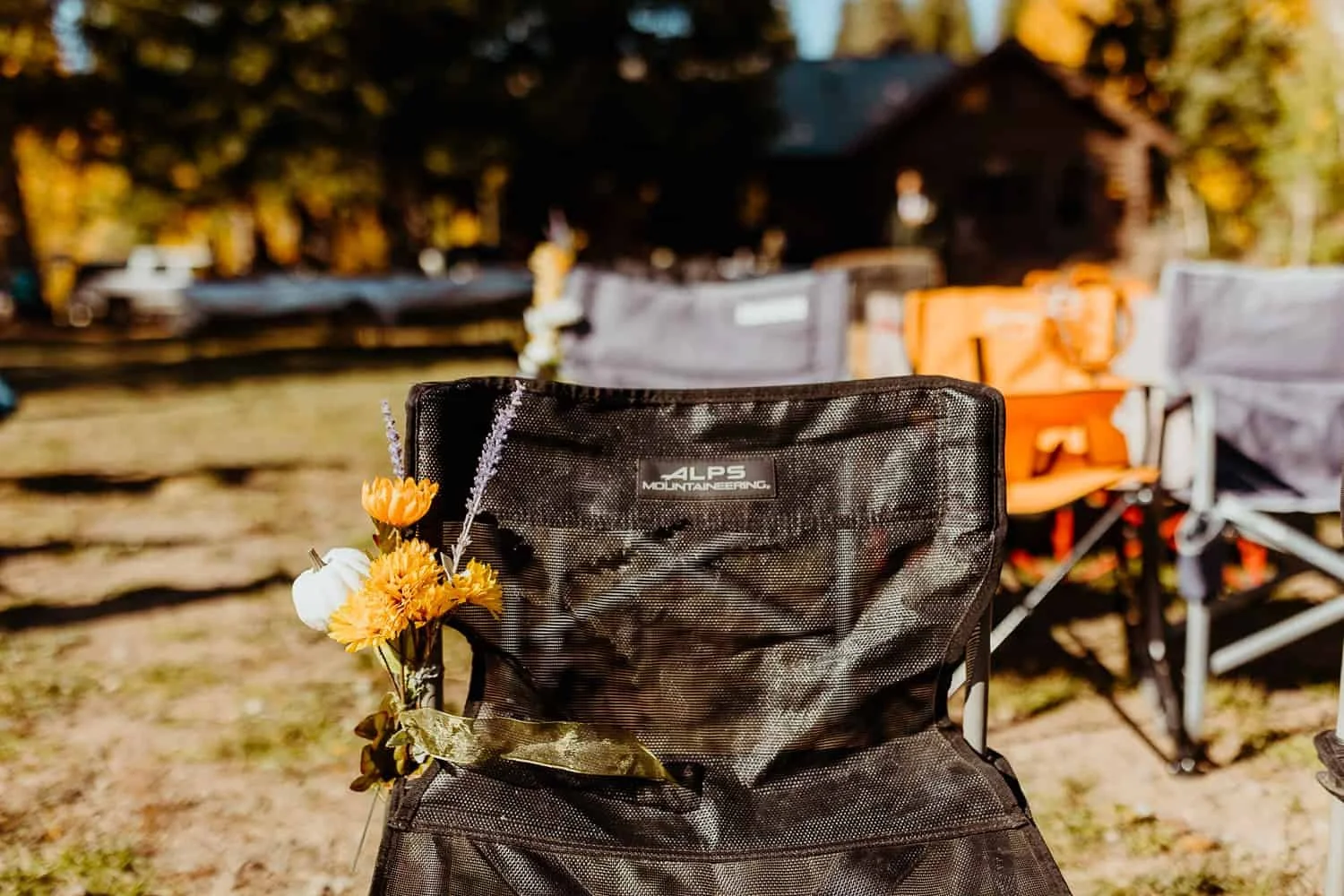 A camp chair decorated with fall flowers at a camp themed reception