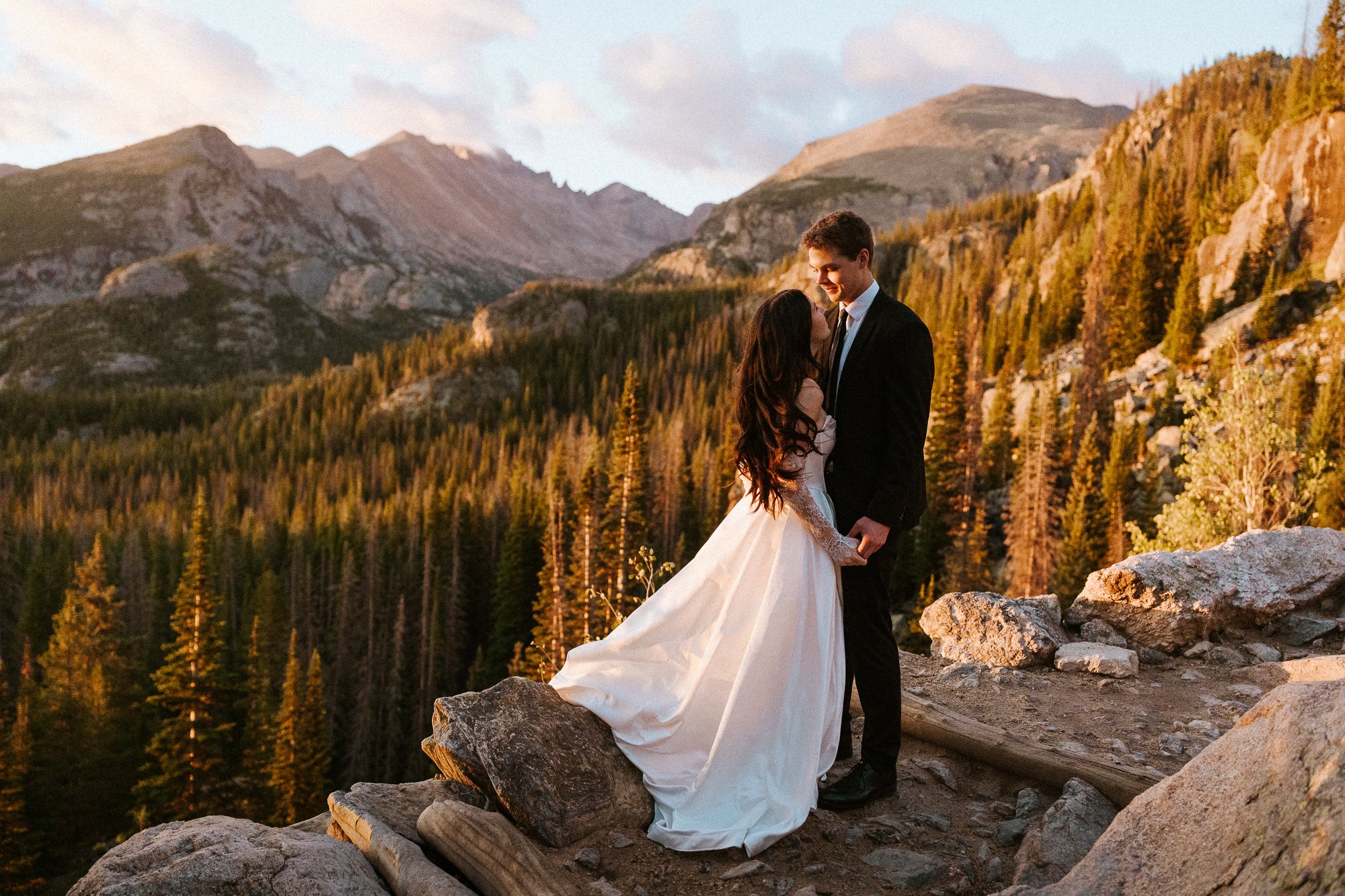 A bride and groom hold hands on the walk to Dream Lake in Rocky Mountain National Park for their elopement