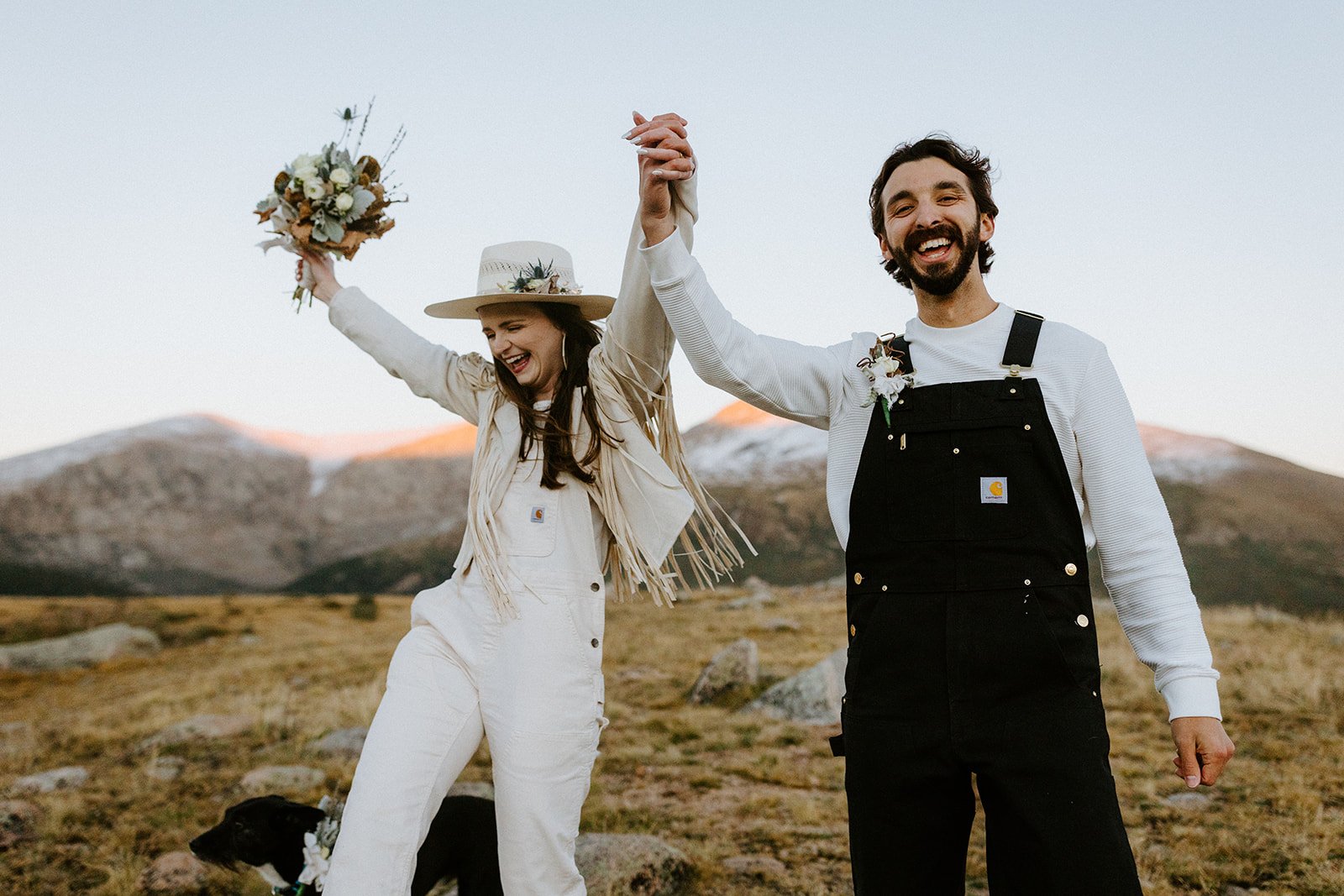 A couple in matching Carhartt overalls celebrates after their microwedding on Guanella Pass
