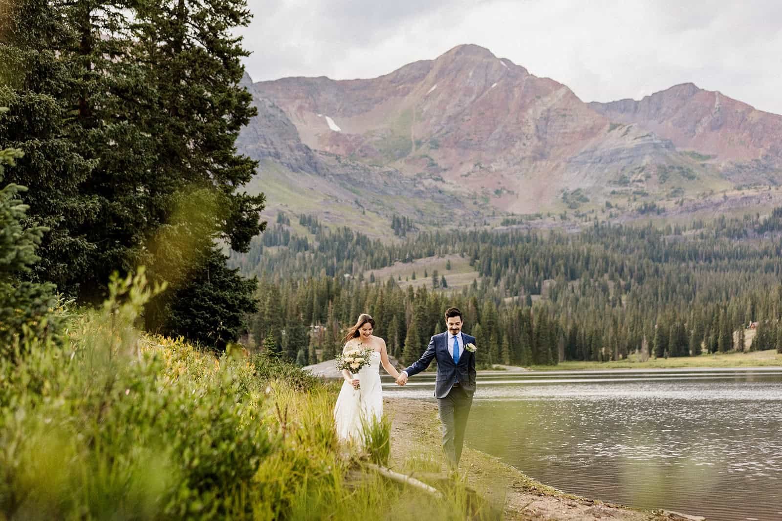 Couple walking along the shore of Lake Irwin, an elopement spot near Crested Butte with peaks behind it