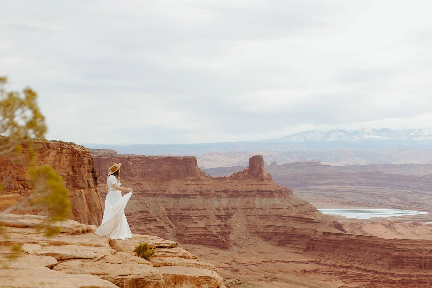 A bride stands on a red rock ledge above Dead Horse Point in Moab
