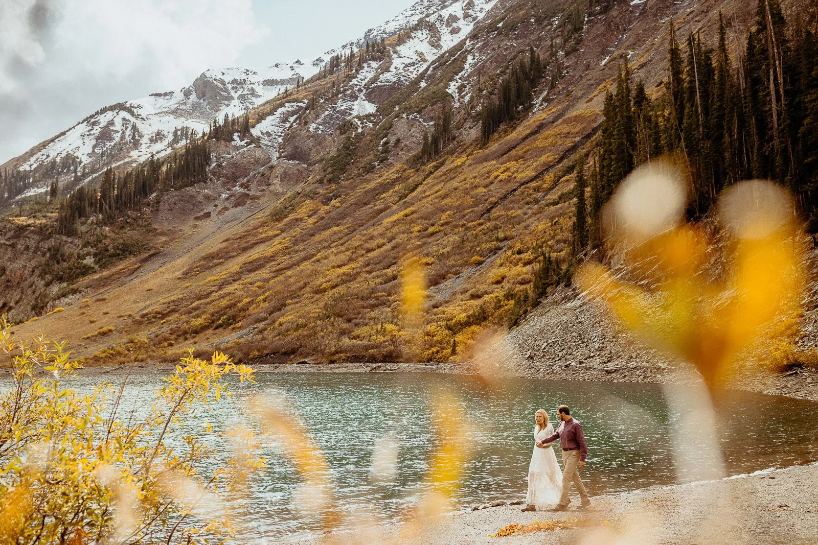A couple during their fall elopement surrounded by golden leaves and an alpine lake in Crested Butte