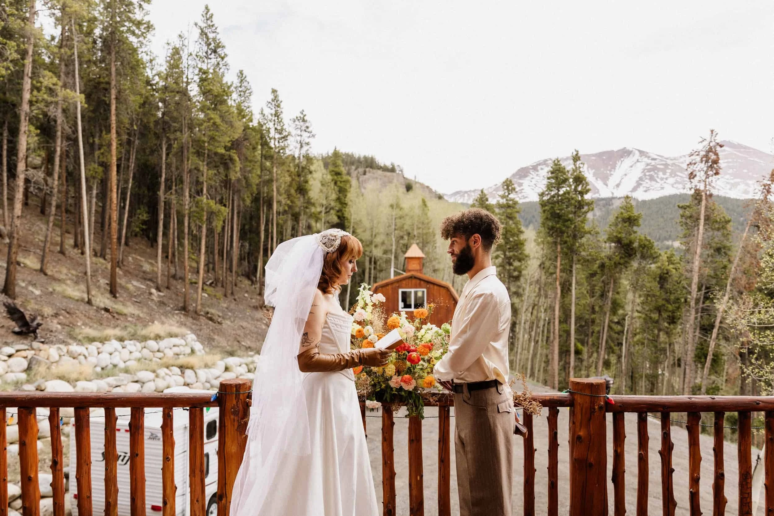 Couple exchanging vows at an outdoor ceremony on a wooden deck surrounded by trees near Leadville, Colorado