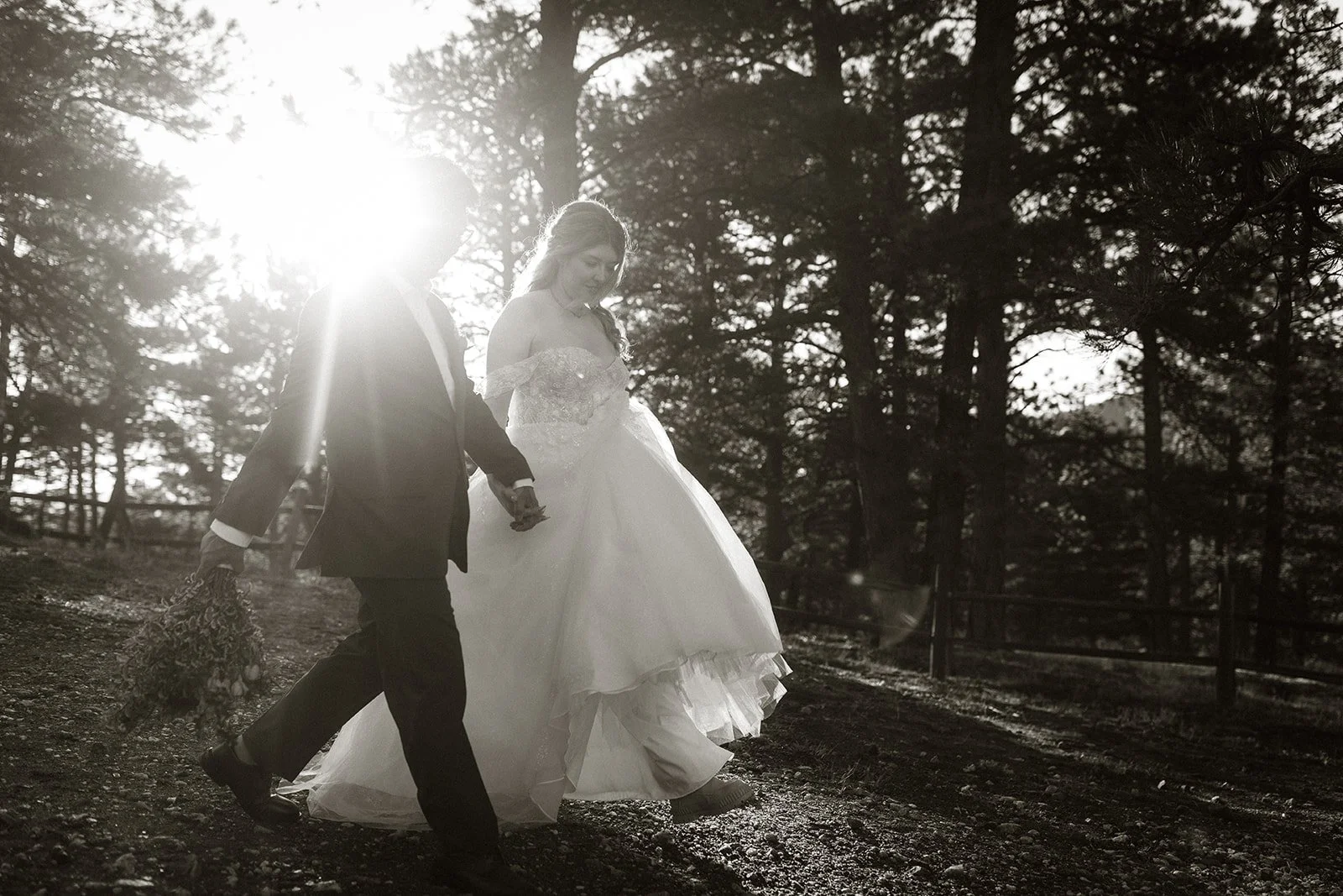 Bride and groom walking down the trail at Lost Gulch holding hands in black and white