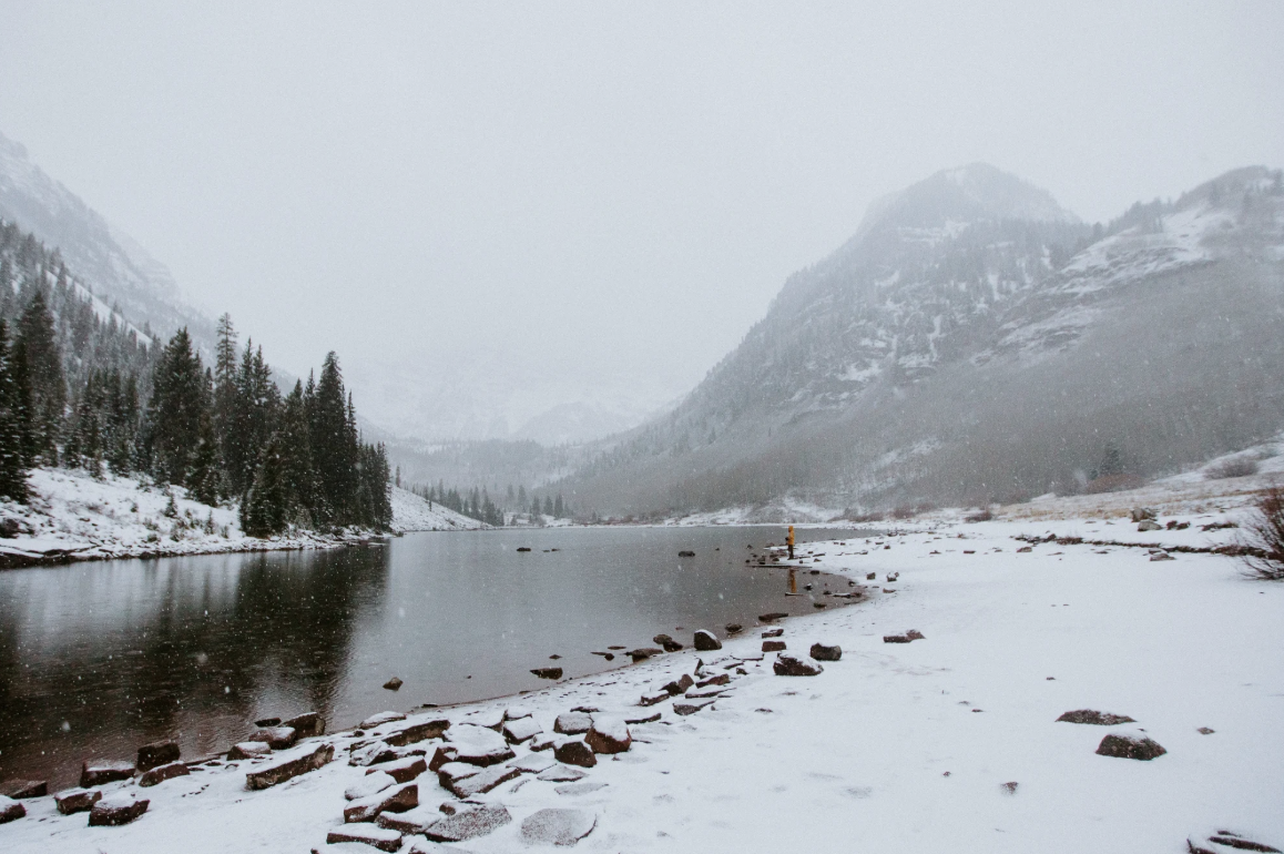 A snowy lakeshore near Aspen with a mountain fading into the clouds and fog