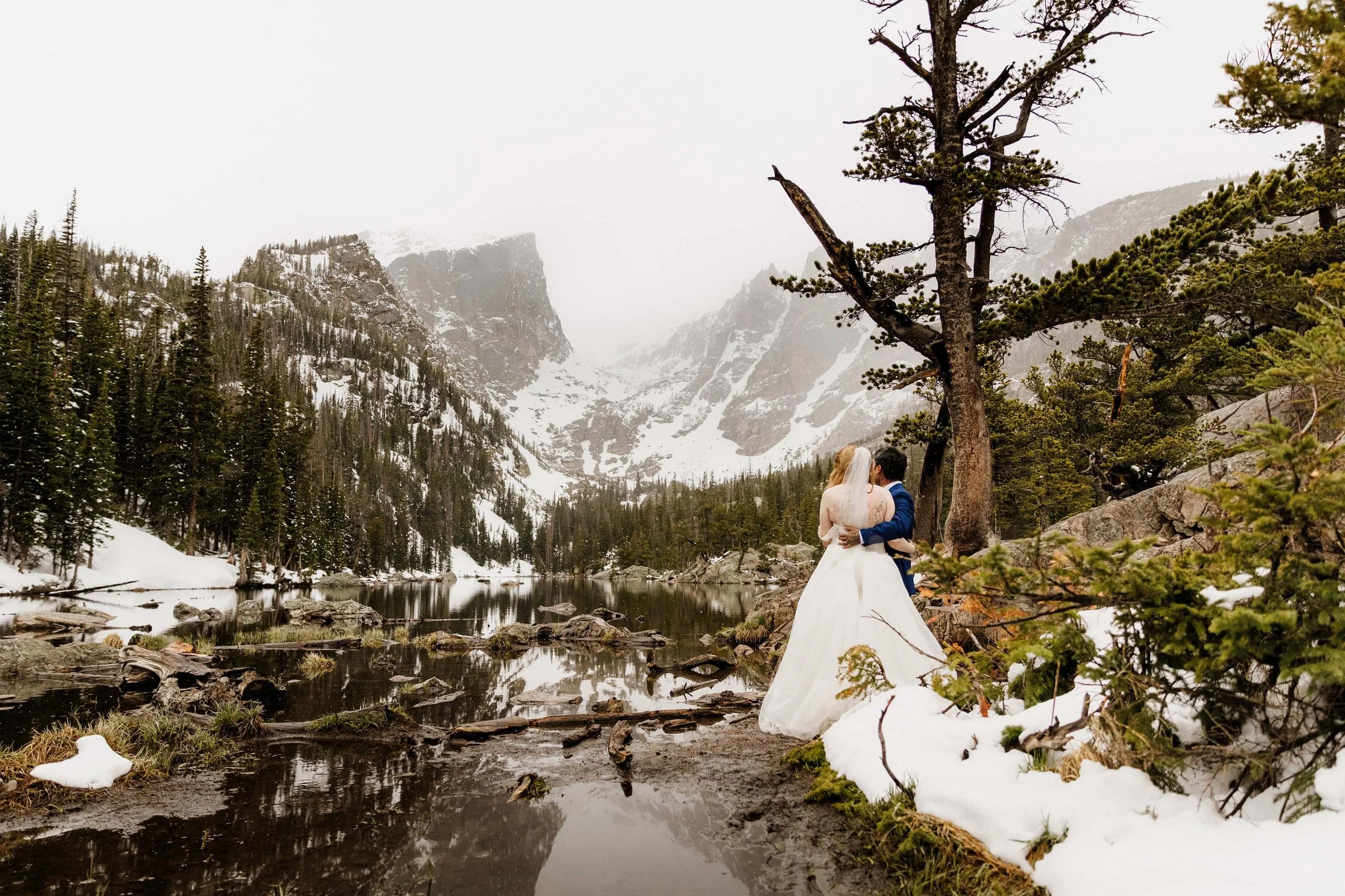 Couple hugging in front of Dream Lake in Rocky Mountain National Park in May
