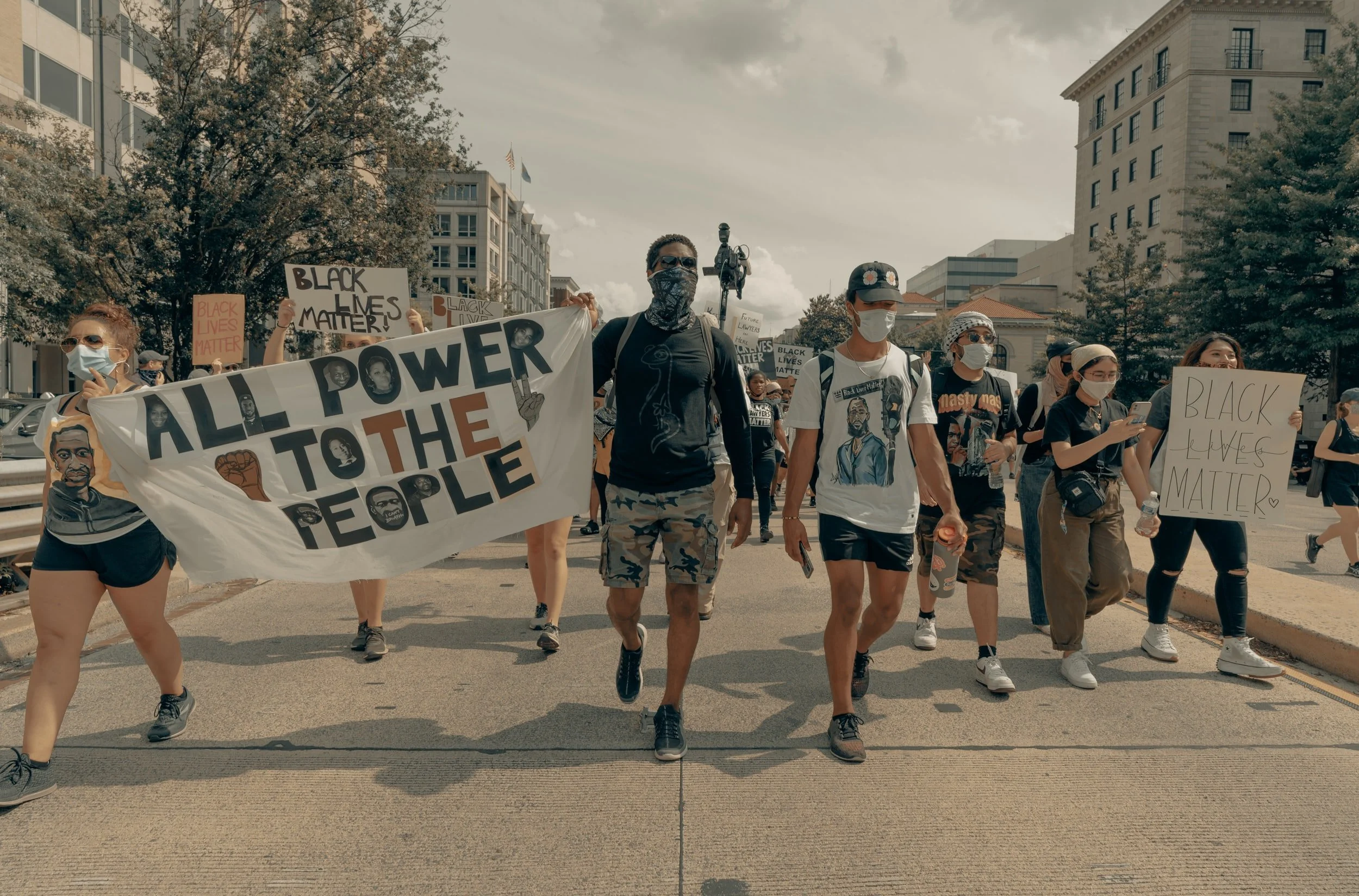 Protesters marching, holding signs that read "all power to the people" and "Black lives matter"