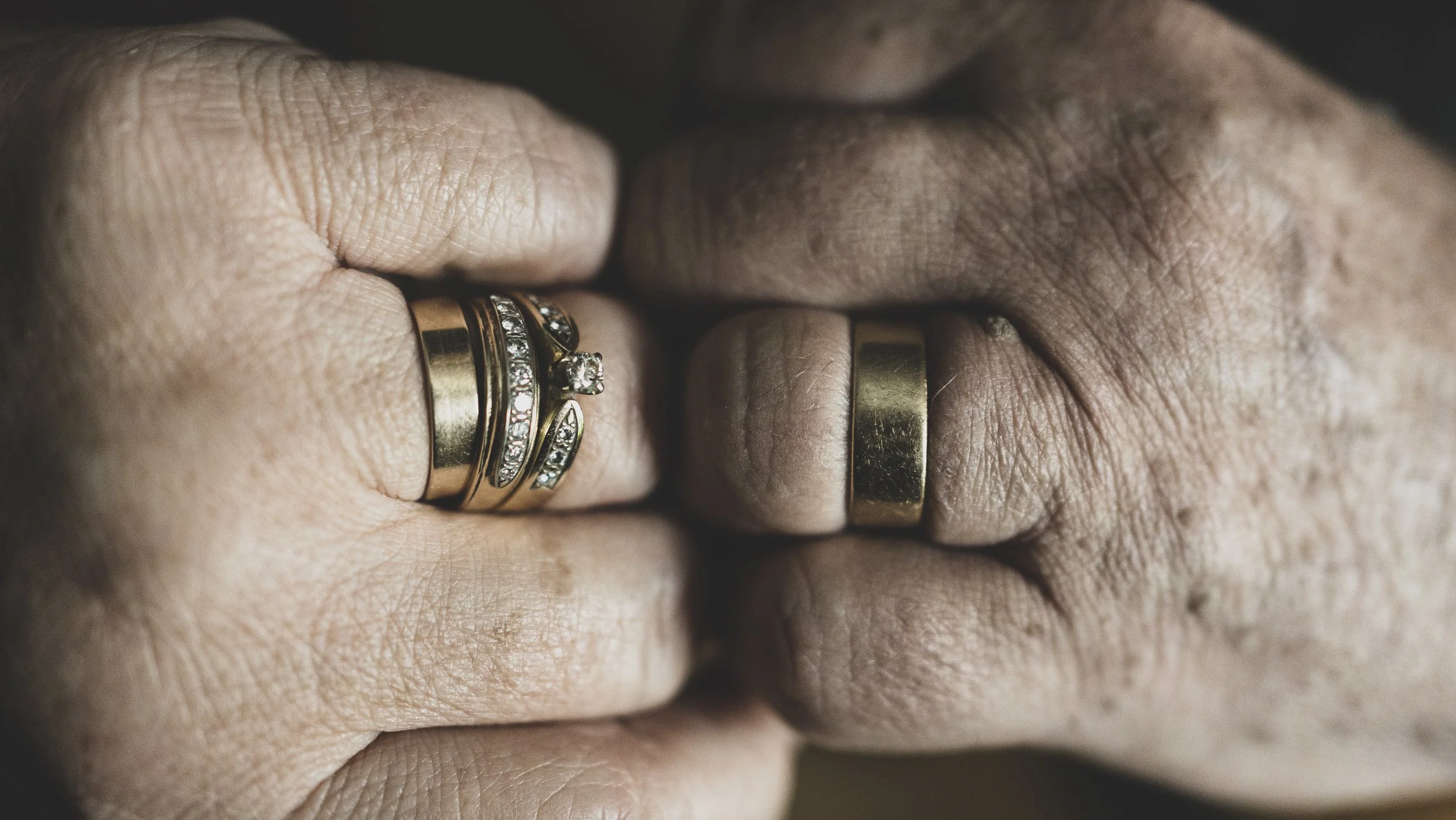 Deux mains avec des bagues en or, certaines ornées de diamants, regroupées.
