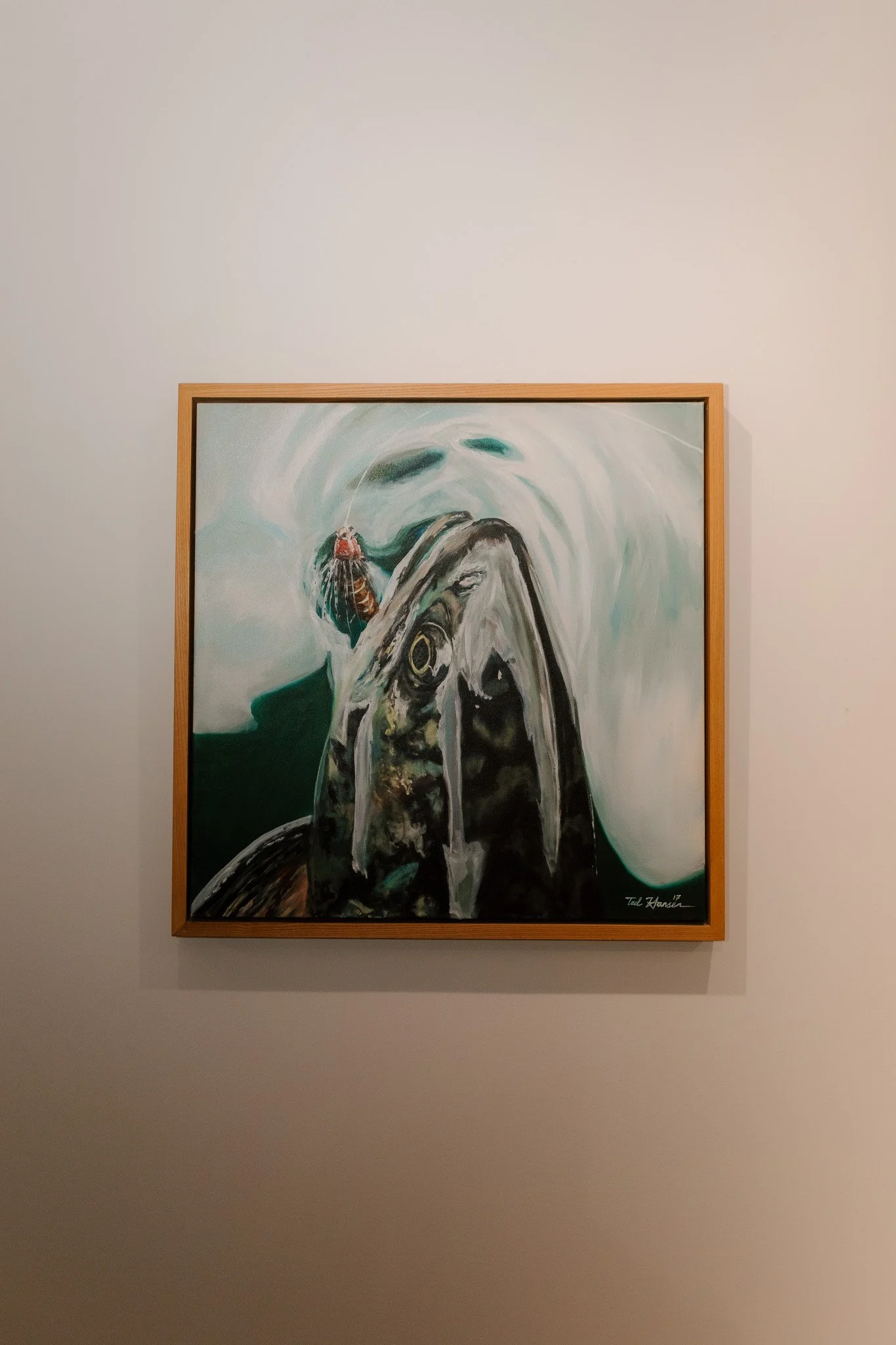 A painting of a fish with a fly on its mouth on a white wall.