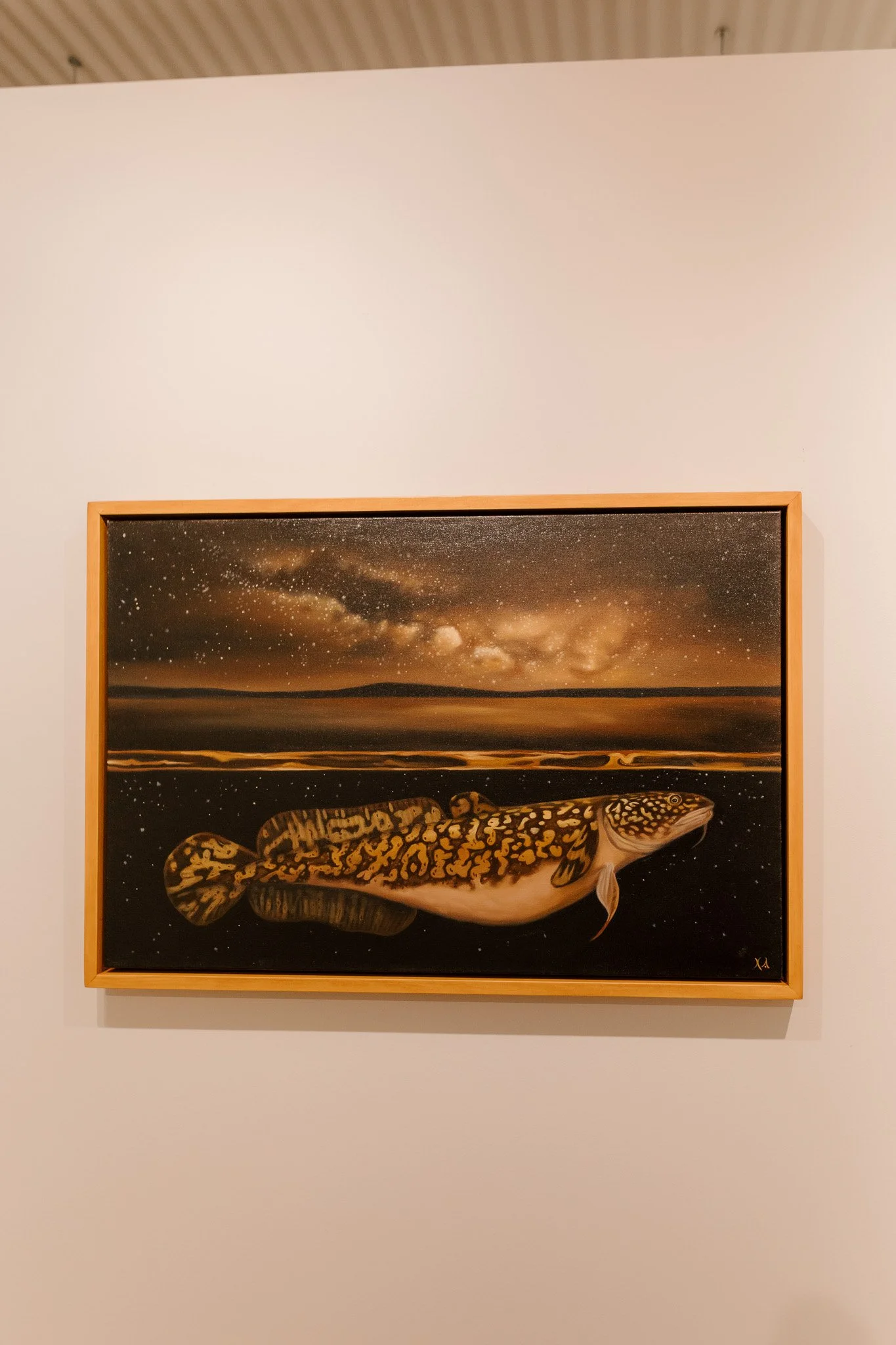 Painting of a fish with detailed markings, set against a starry night sky with the Milky Way, on a dark background.