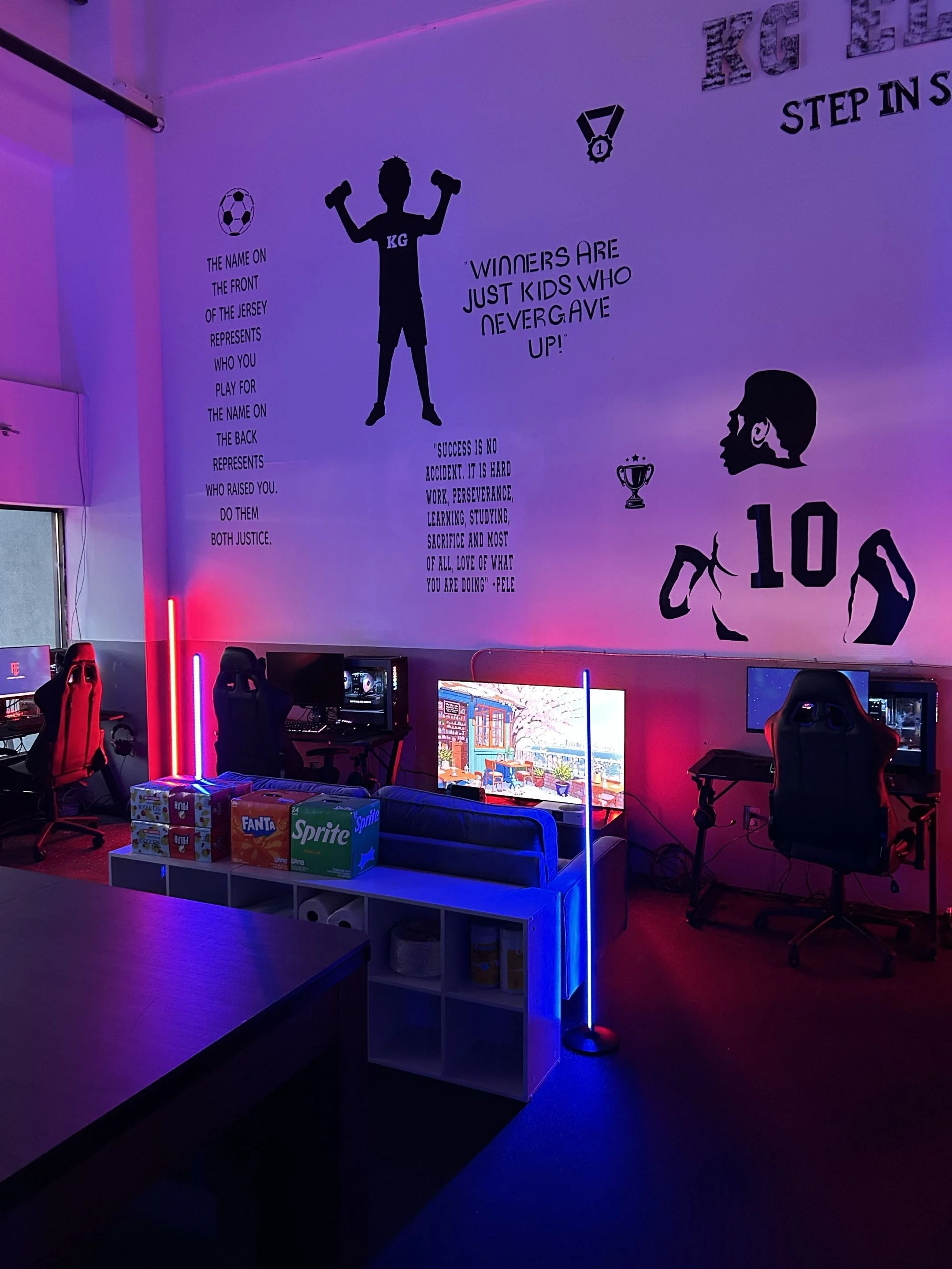 Gaming and esports lounge with multiple gaming stations, a ping pong table, and sports-themed decor and artwork.