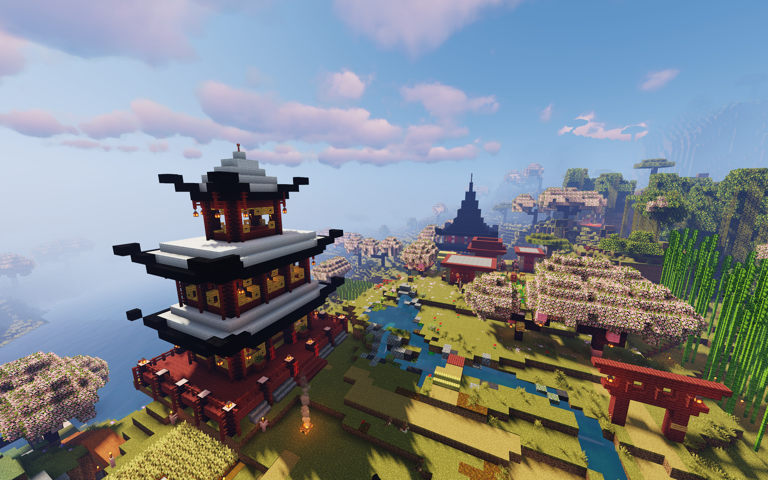 Minecraft landscape featuring traditional Asian-style pagoda buildings, cherry blossom trees, a flowing stream, and lush green surroundings under a partly cloudy sky.