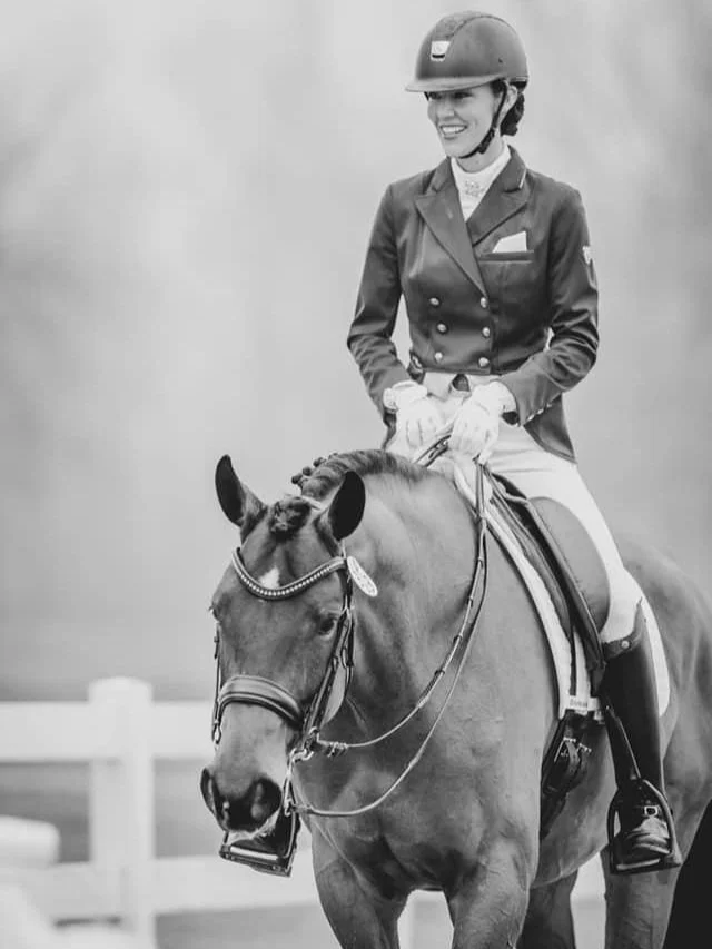 A woman dressed in equestrian attire riding a horse.