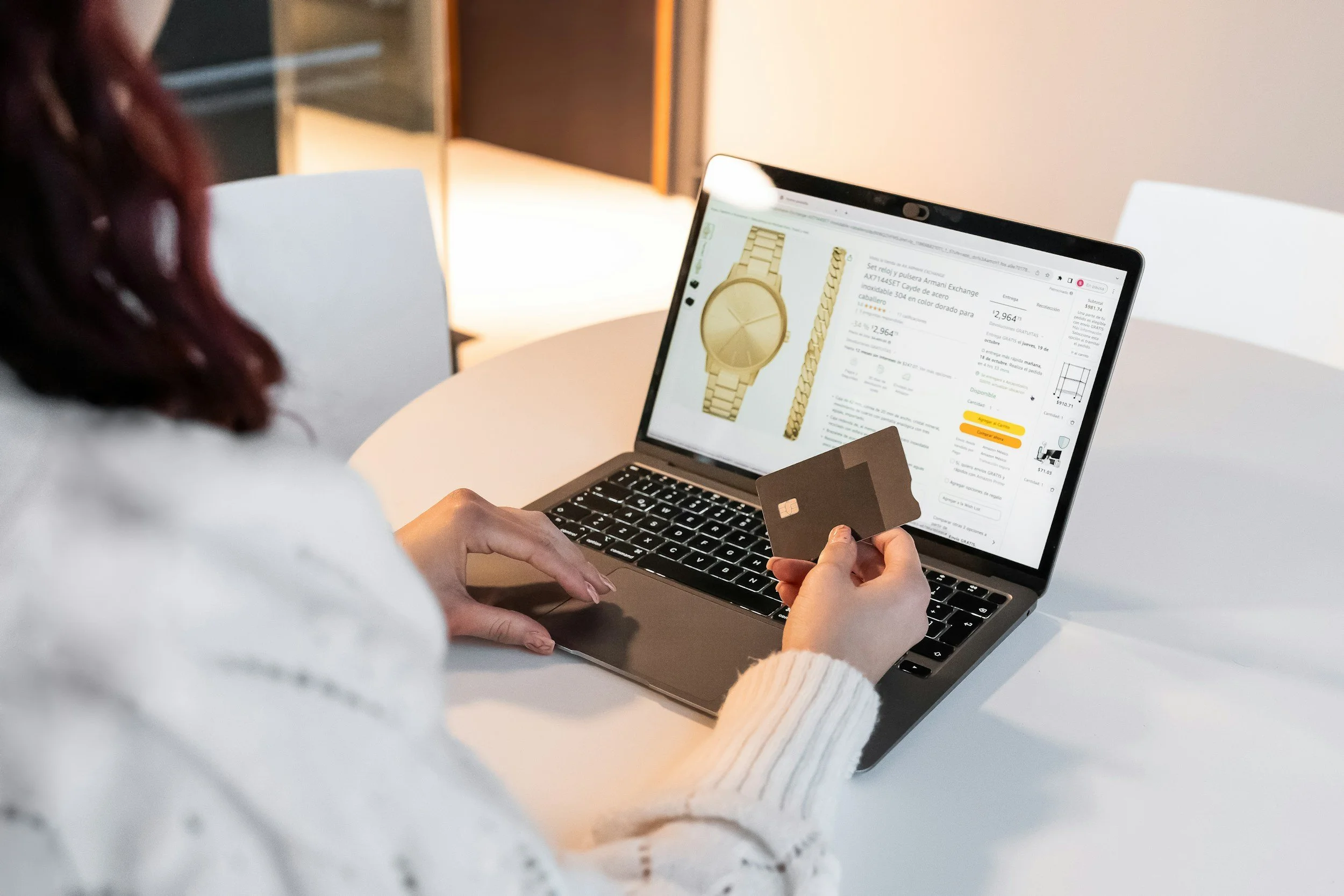 Woman holding black bank card while shopping online for a gold watch.
