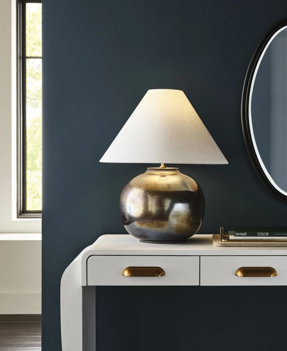 The Italian ceramic Borgia Lamp atop a white desk with a dark blue wall backdrop.