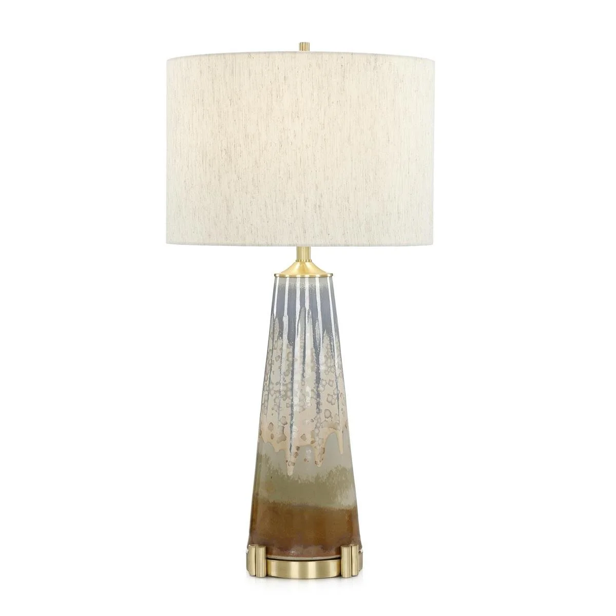 The Overflow Table Lamp rests on a dimensional Brushed Brass base and is topped with a light grey linen drum shade and a coordinating brass peg finial.