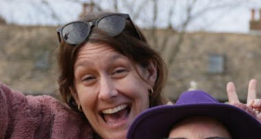 a white woman with brown hair, sunglasses on her head.