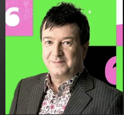 a white man , wearing a grey jacket and colourful shirt , colour background with a number 6