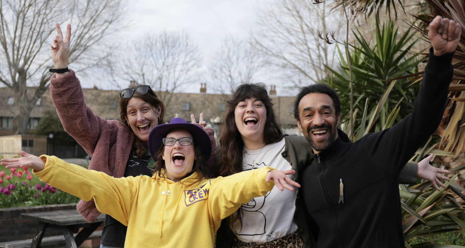 a group of 4 people in a garden celebrating , facing the camera.