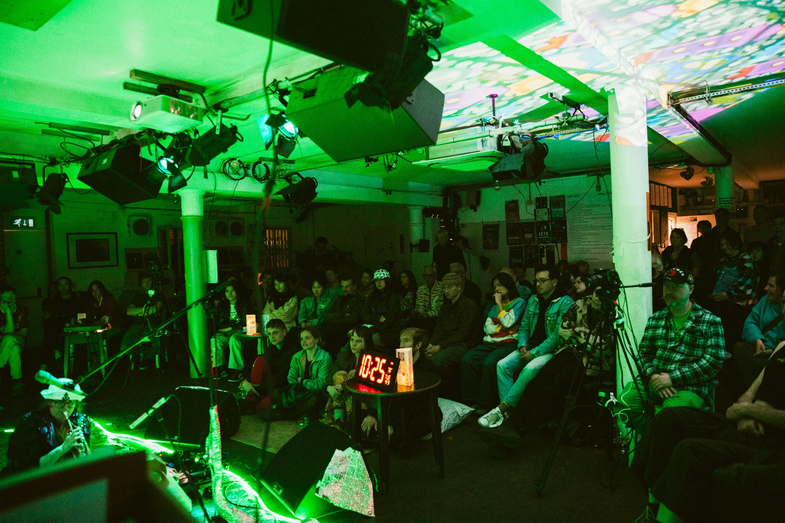 a room with a lot of green room , people sat on chairs