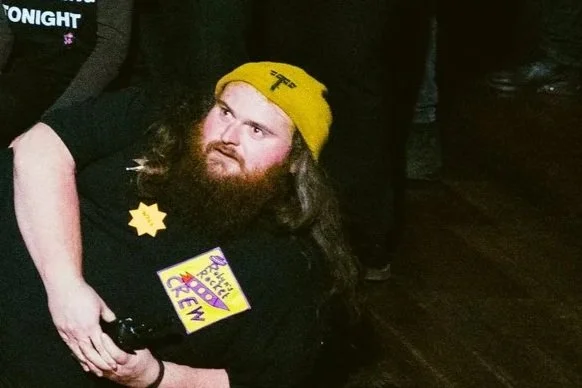a white man with a yellow hat , long hair and a beard.