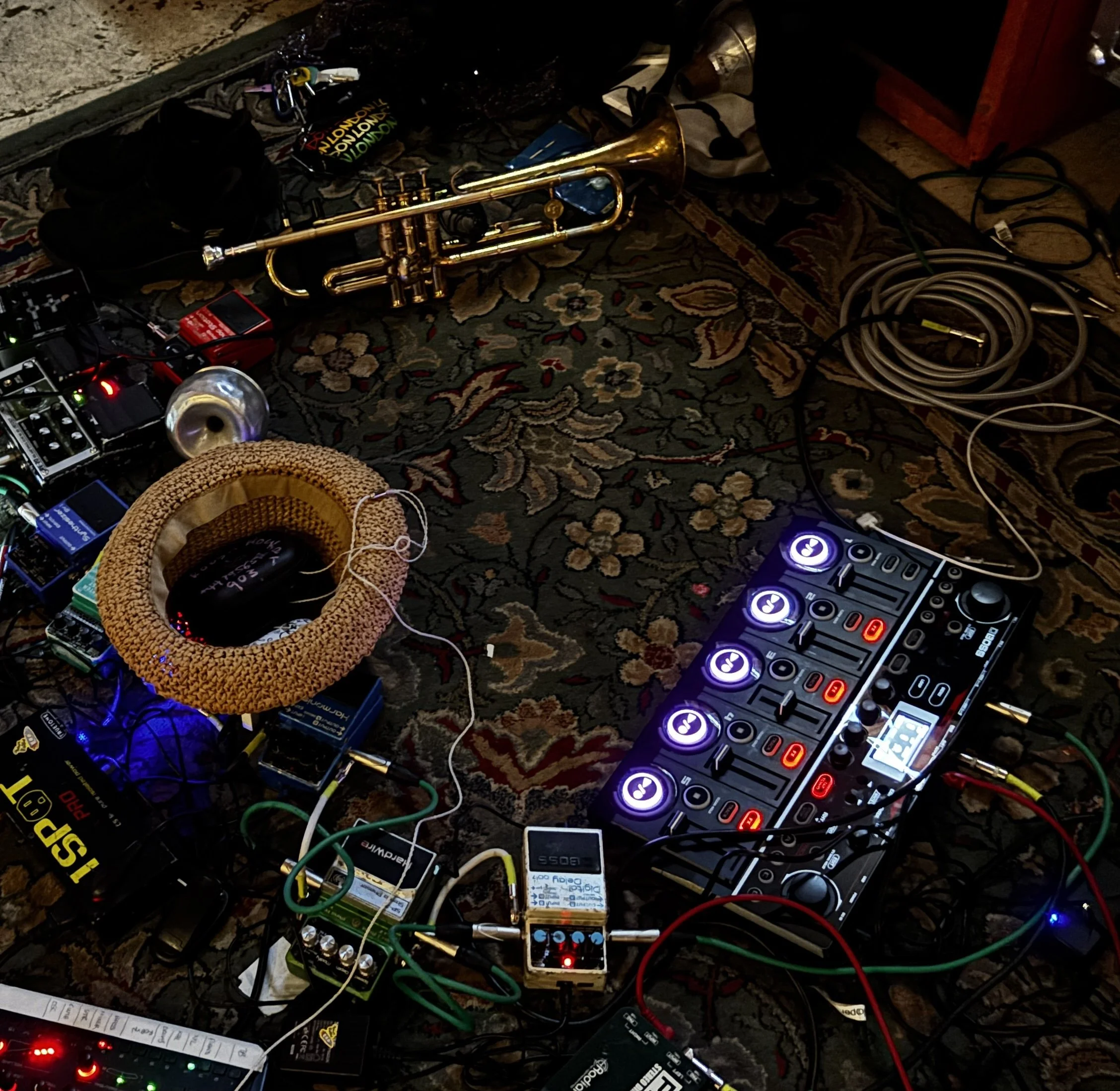 a carpet with a trumpet , hat and lots of guitar pedals.