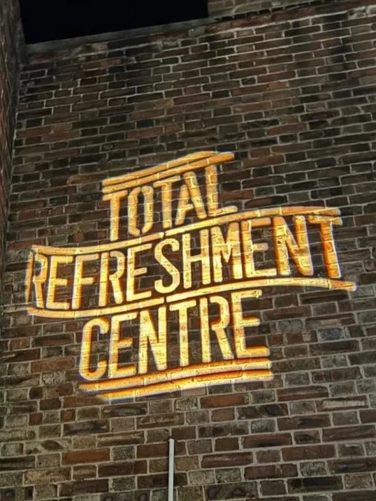 a wall with the words TOTAL REFRESHMENT CENTRE projected on to it