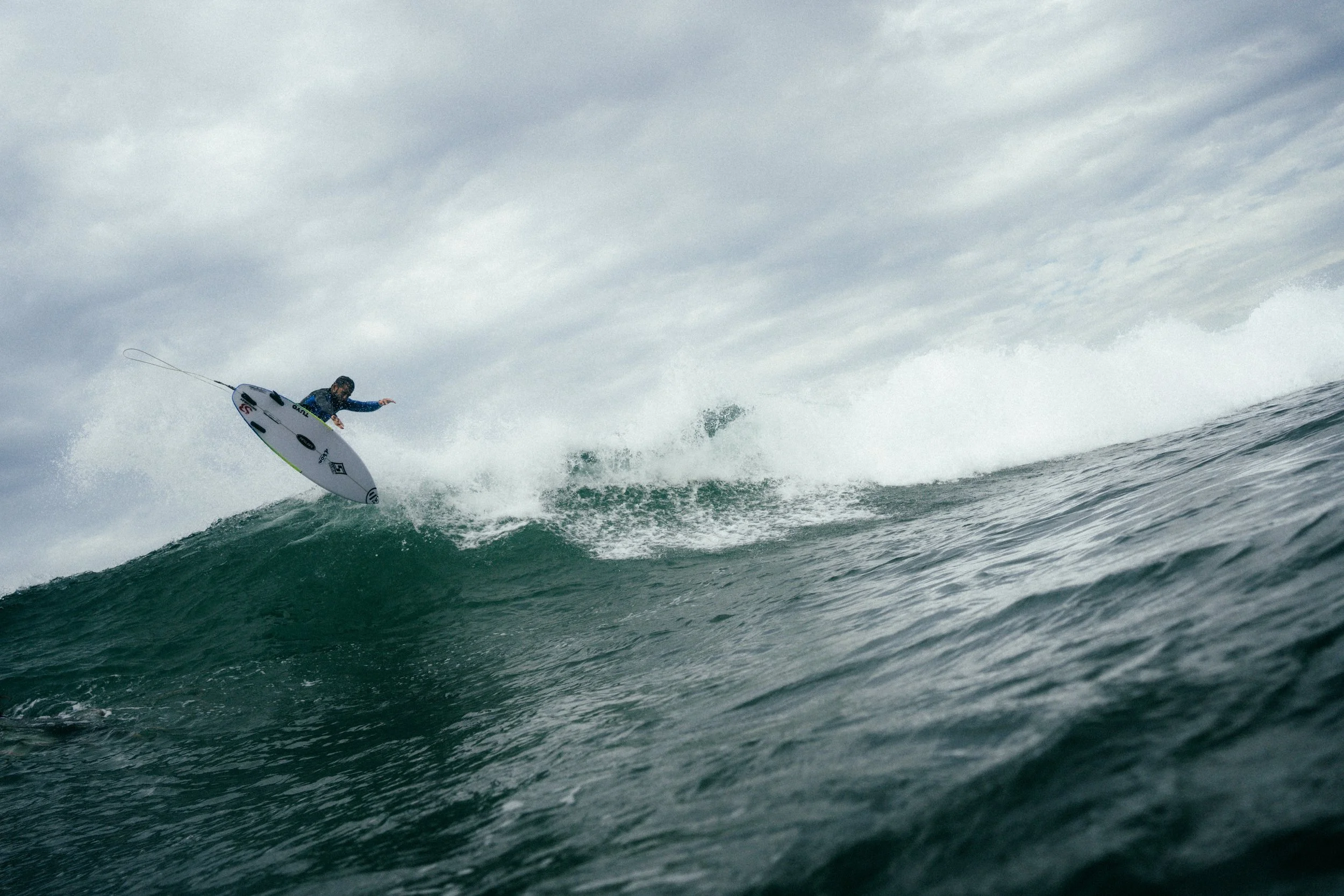 A person surfing on a wave in the ocean during overcast weather.