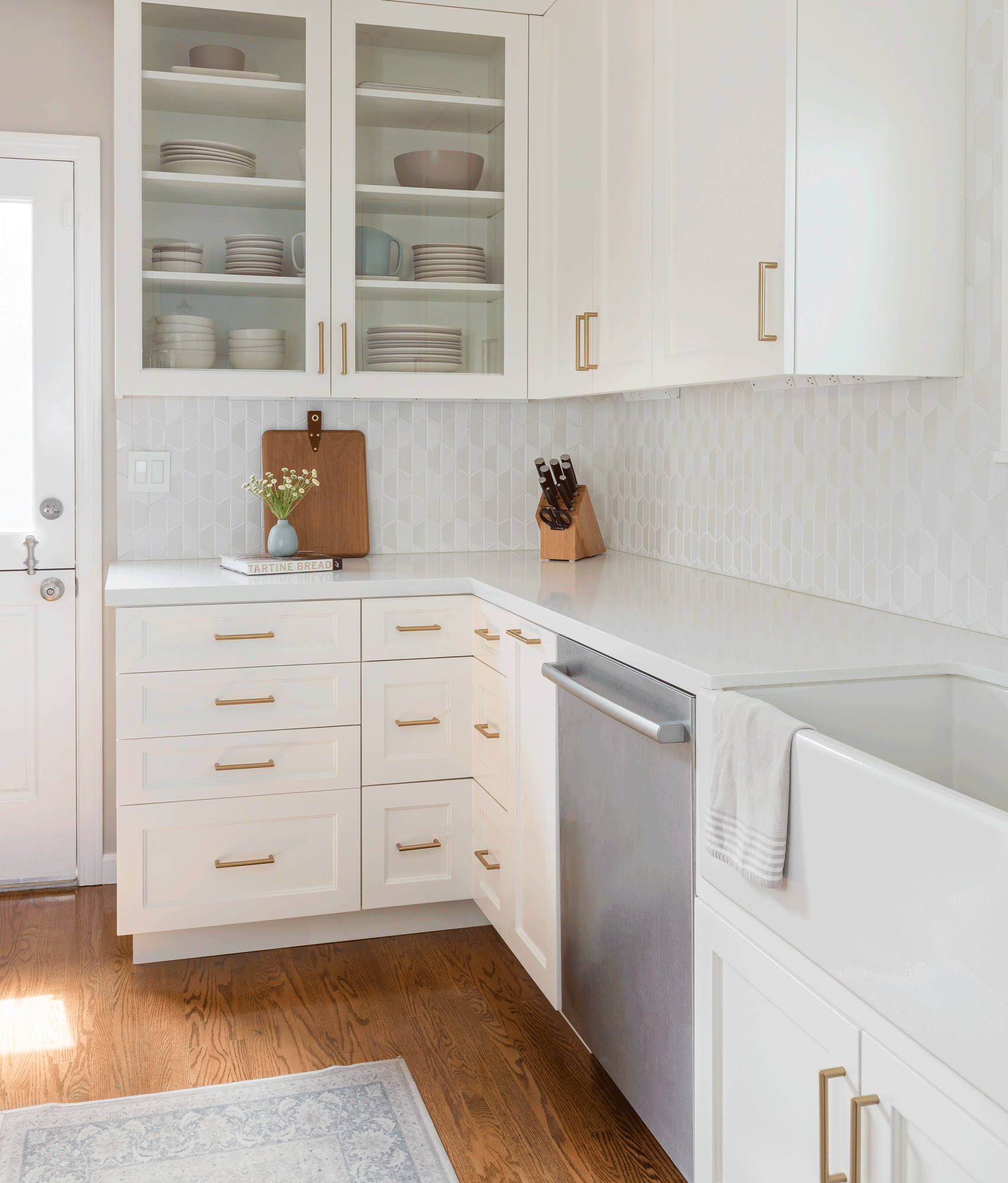 White shaker kitchen with brass hardware, geometric tile backsplash, and farmhouse sink in a Beach Cities home remodel