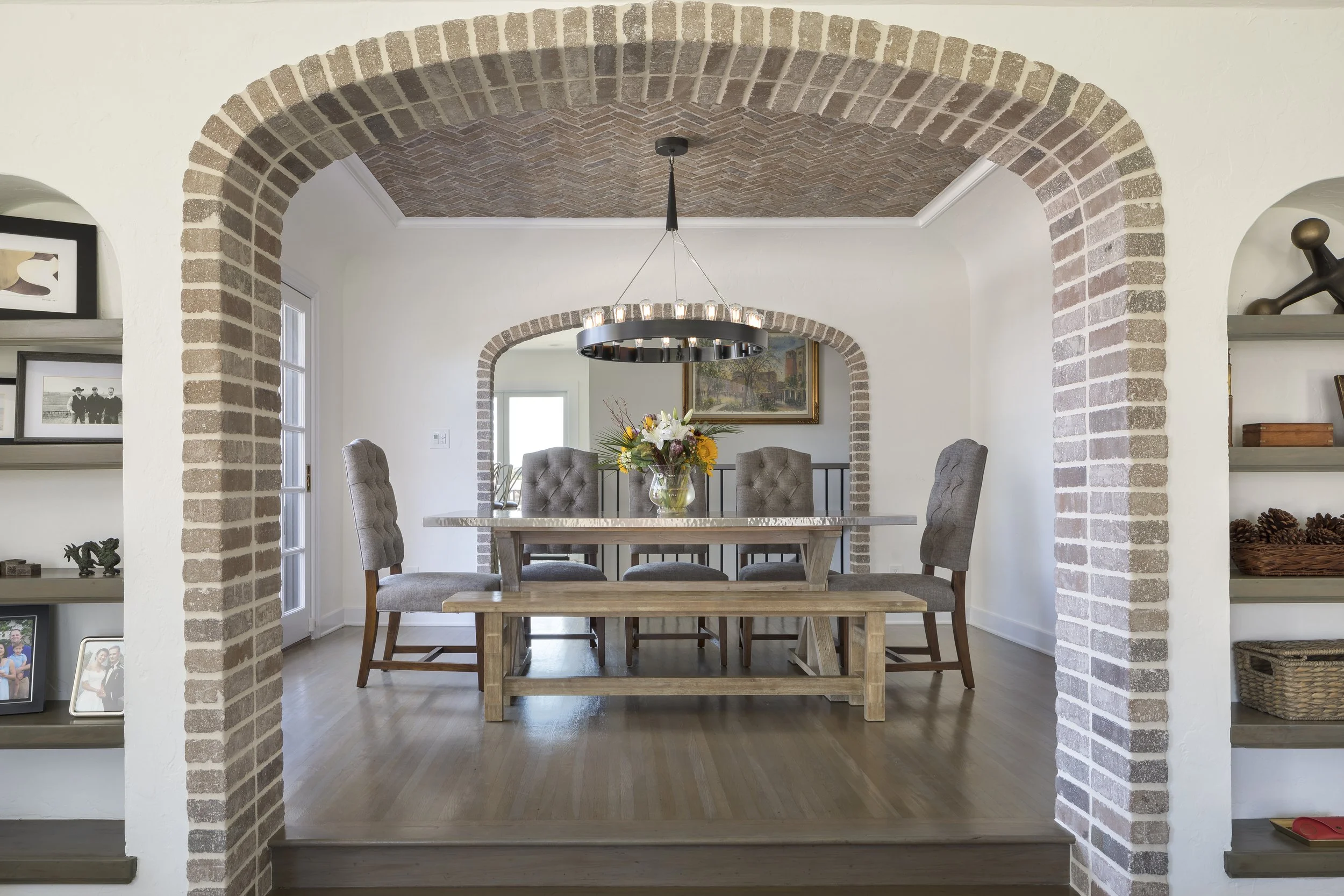 Dining table and chairs visible through exposed brick archway