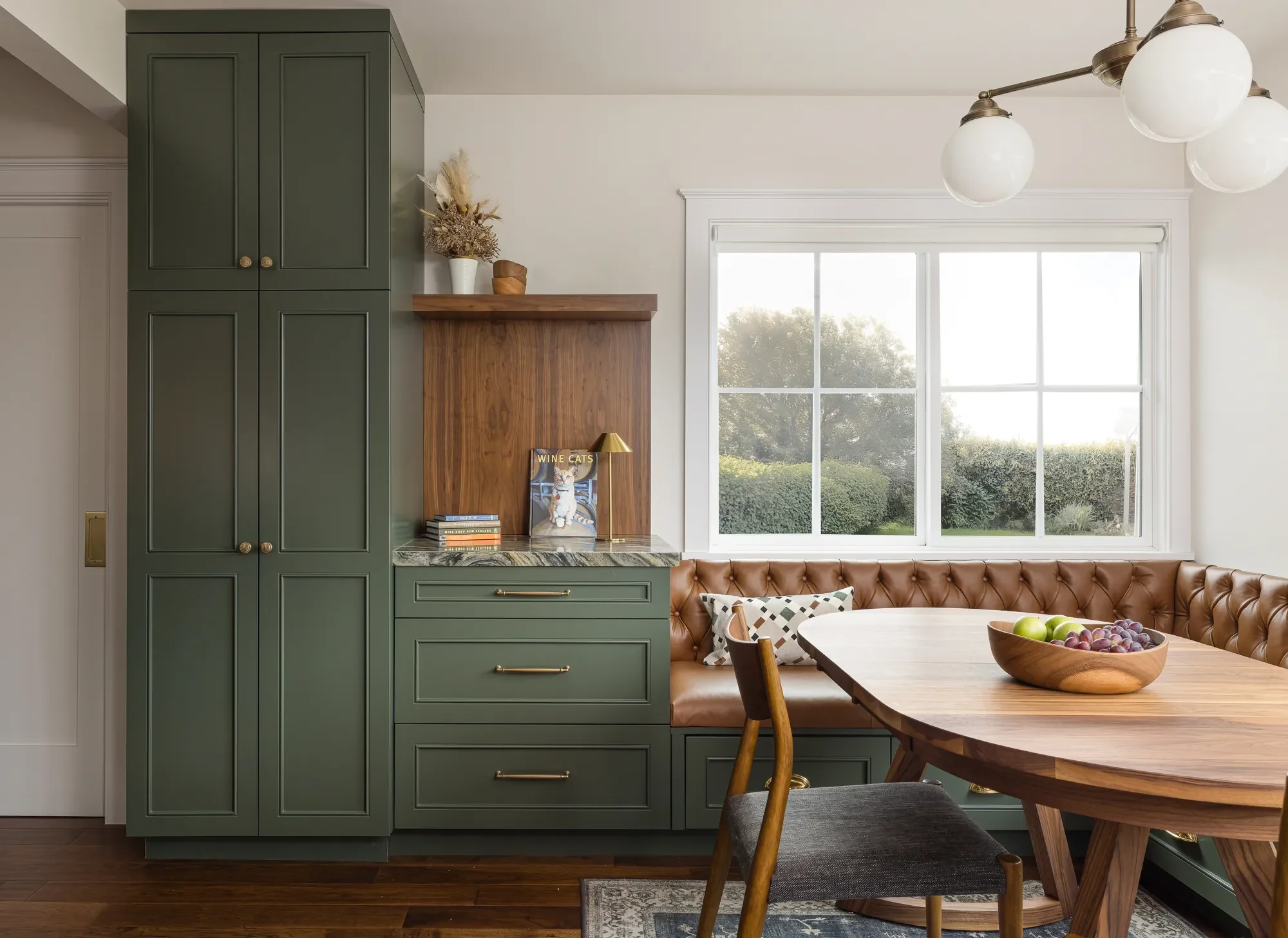 Leather banquette seating and green cabinetry in a Craftsman kitchen to living room transition in Hawthorne