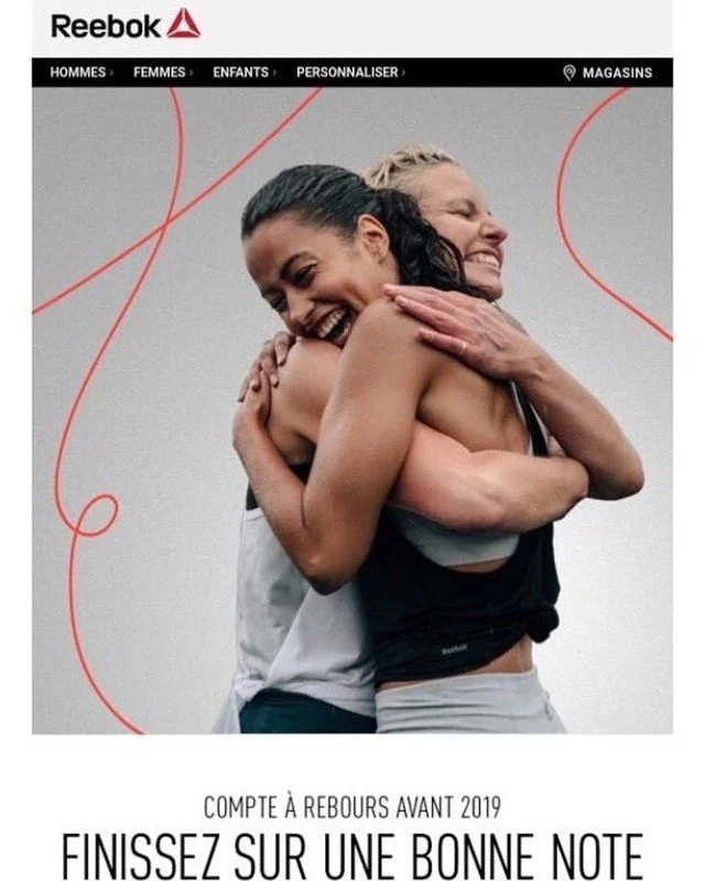 Two women hugging and smiling. Reebok advertisement in French promoting fitness before 2019, with navigation menu at the top.