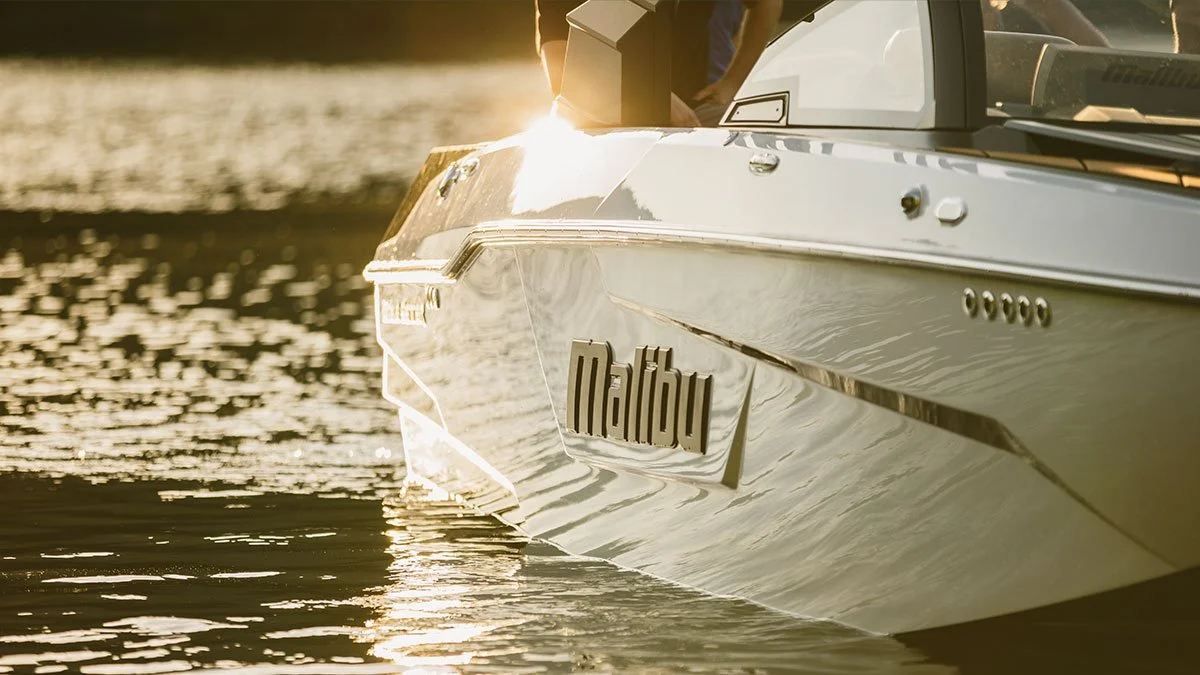 Close-up of a white Malibu boat on calm water at sunset