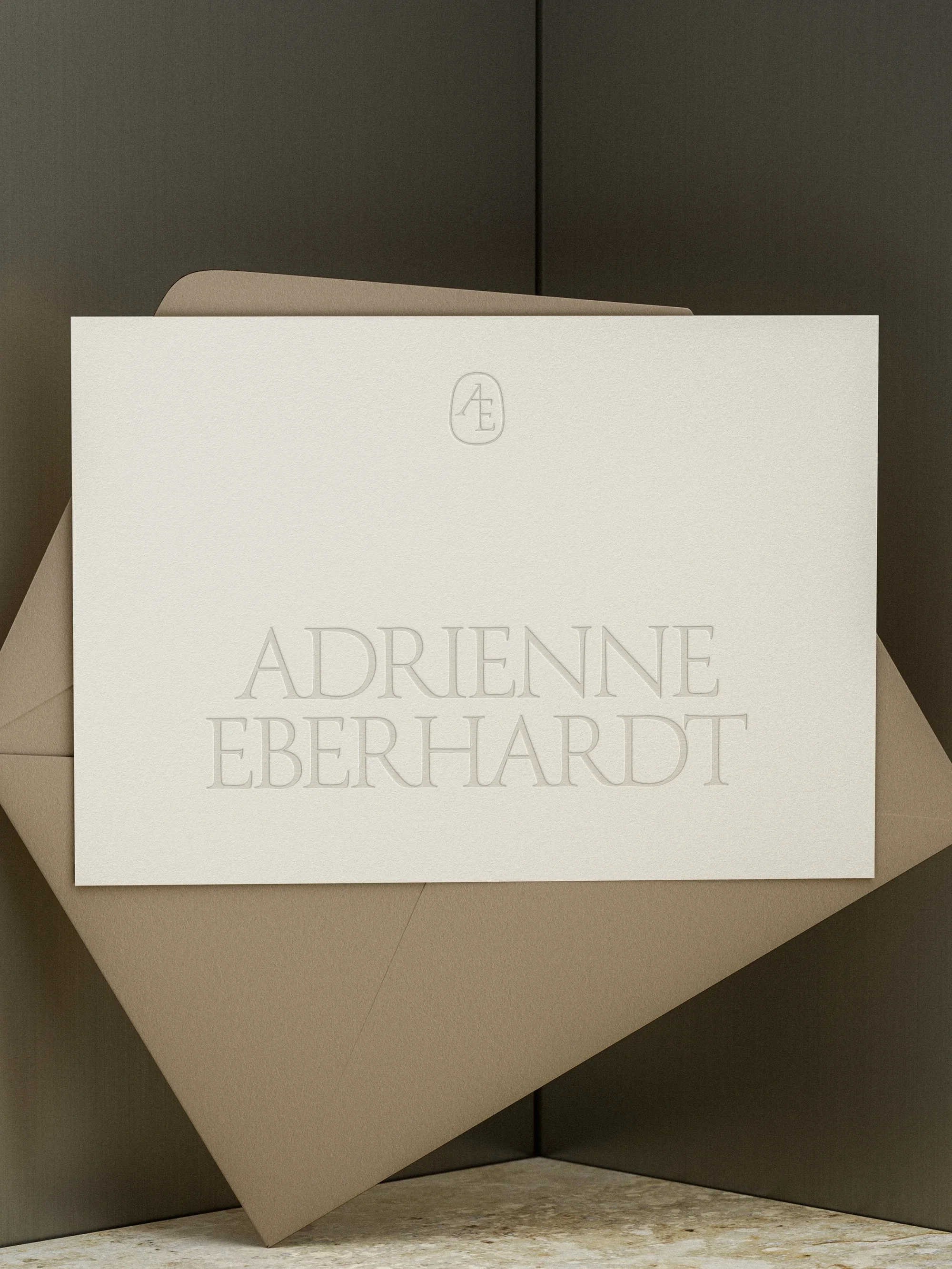 A white book with the title 'Adrienne Eberhardt' embossed on the cover, leaning against a beige and dark grey geometric background.