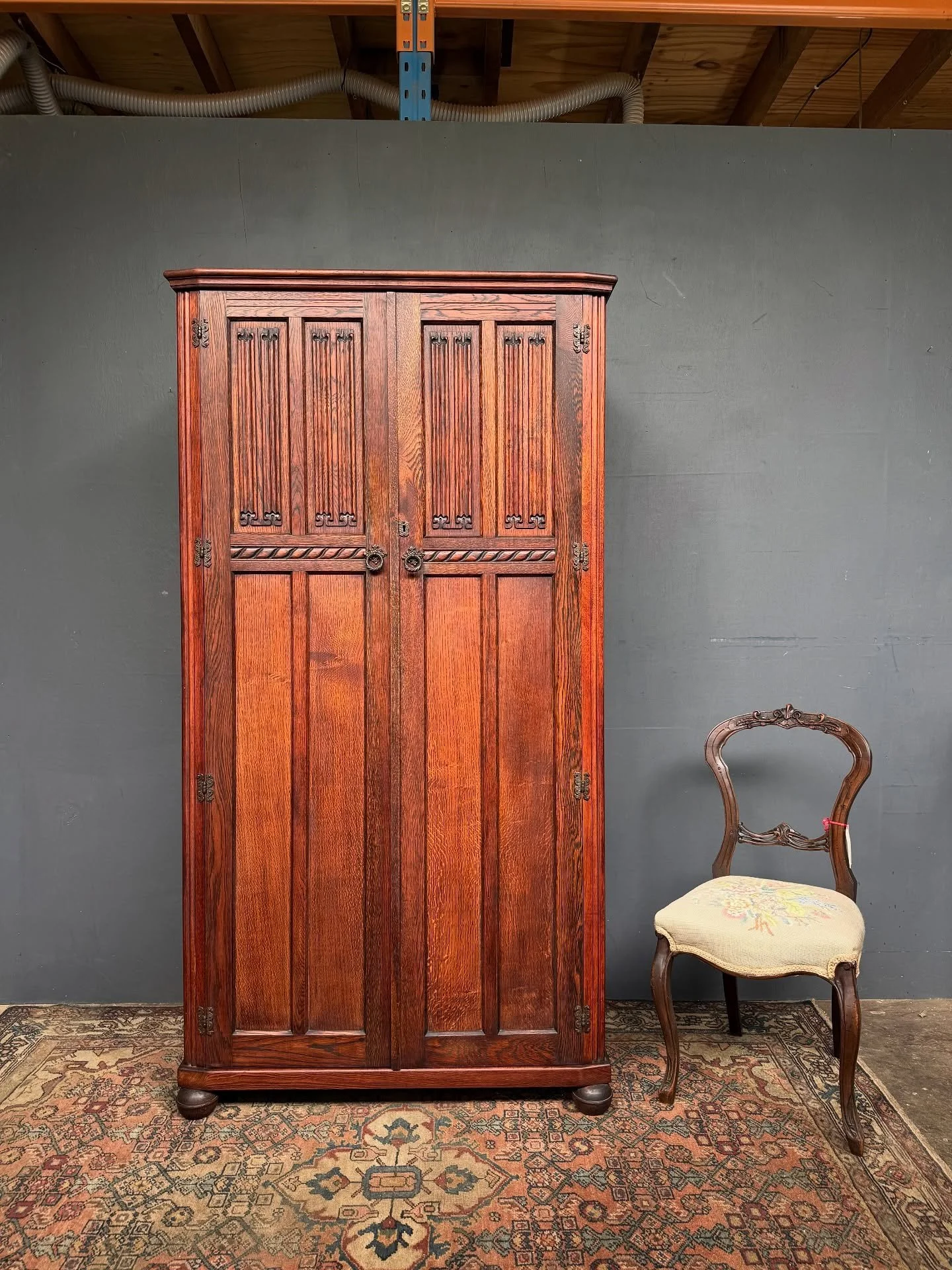 Vintage, Mid 20th Century wardrobe.  The Linen fold details to the doors are lovely. Oak and Oak veneer. Made in England. 
Hanging to the left, which easily fits a modern hanger, and compartments to the right with labels, reading Shirts, Underwear, P