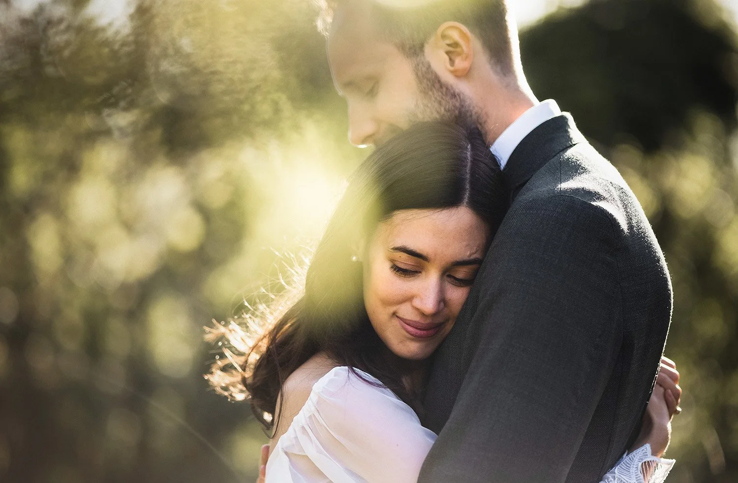 Brud och brudgum omfamnar varandra i varmt motljus under en romantisk bröllopsfotografering utomhus.