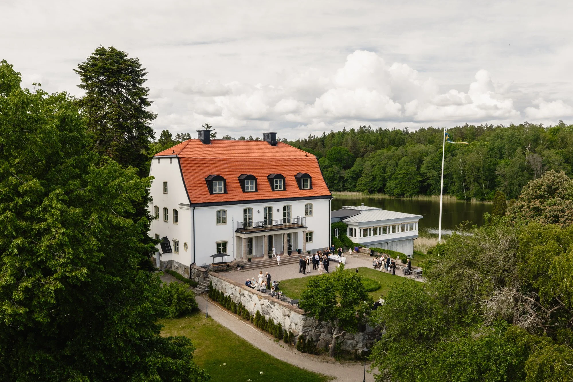 Drönarbild över Tammsviks herrgård vid Mälaren med bröllopsgäster på terrassen